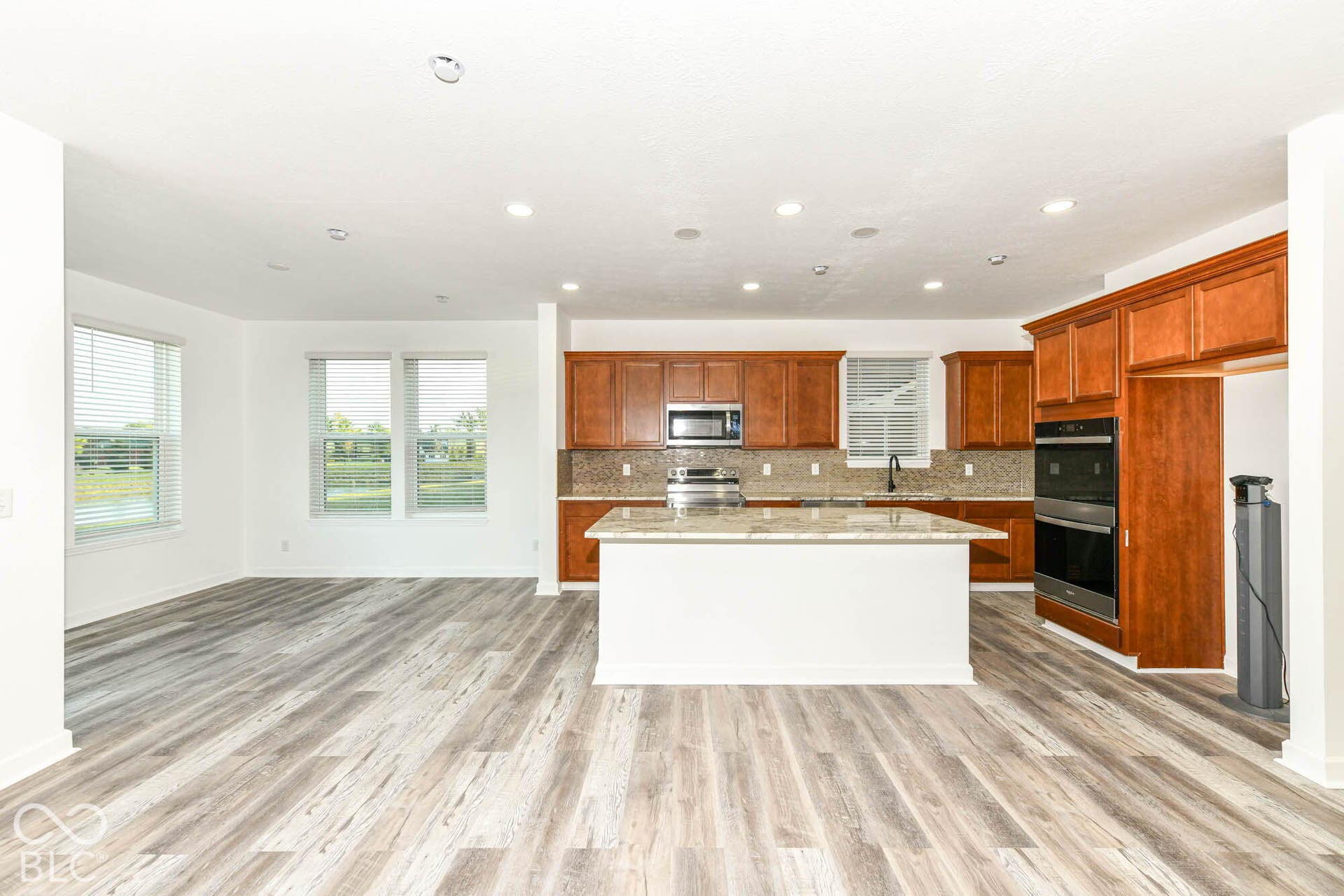 Spacious kitchen featuring a large island, wood cabinetry, built-in double ovens, and a microwave