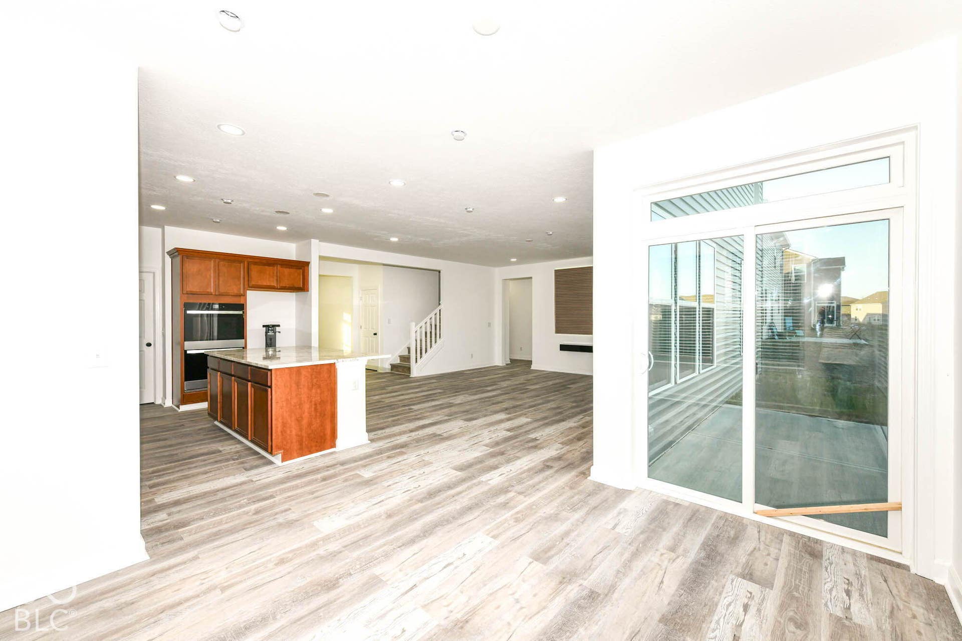 Open-concept living space with wood-finish flooring, recessed lighting, and a kitchen island featuring a light-toned countertop