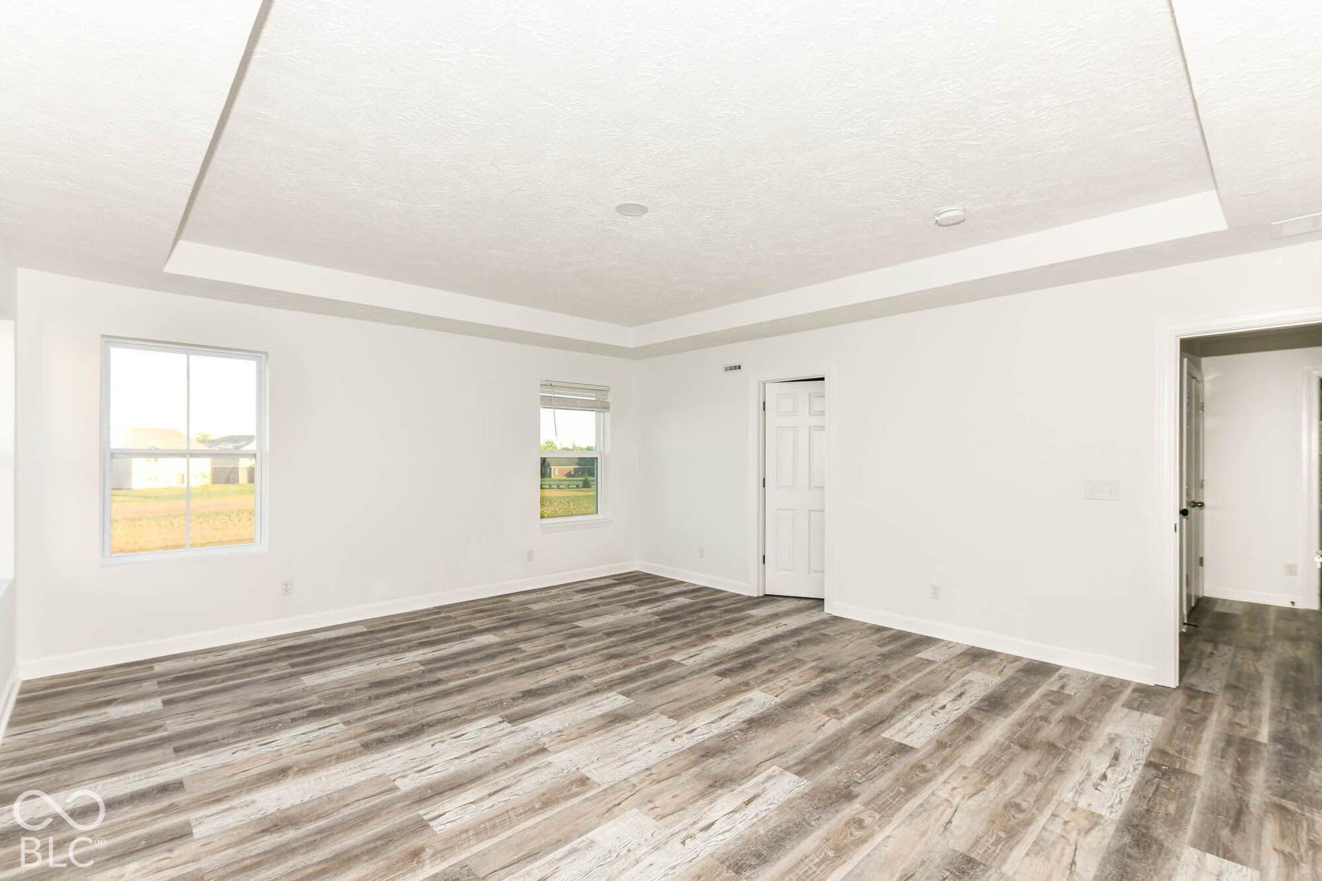 Tray ceiling, wood-finish flooring, recessed lighting, and multiple windows