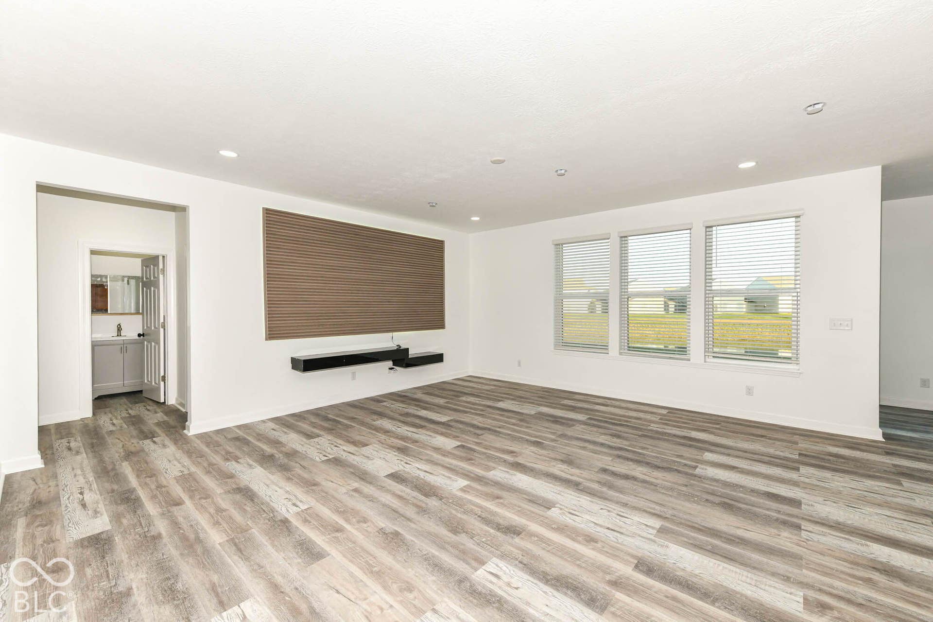 Wood-finish flooring throughout, integrated floating shelves, recessed lighting, and triple windows with blinds