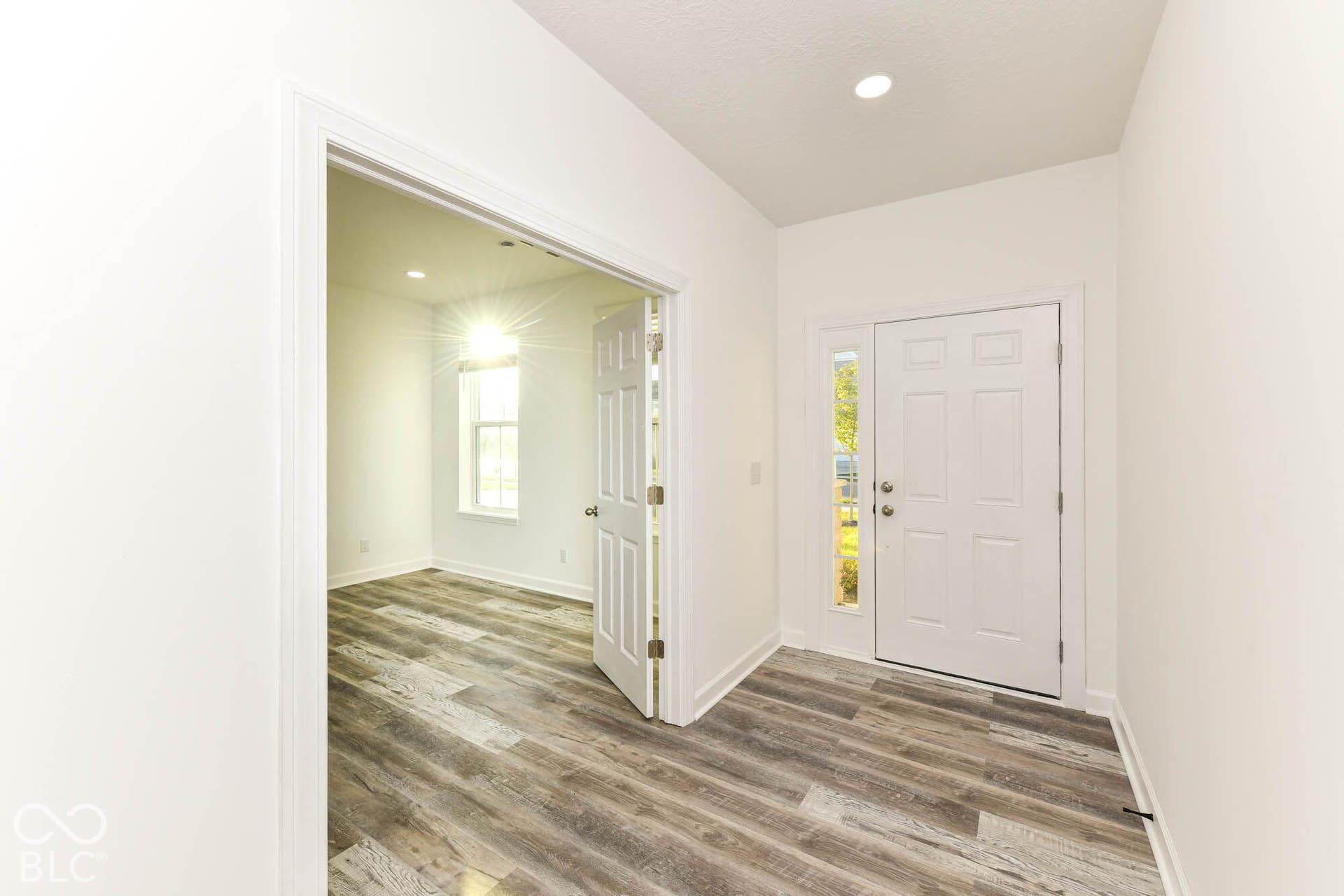 Entryway featuring wood-finish flooring and a white paneled door with a sidelight