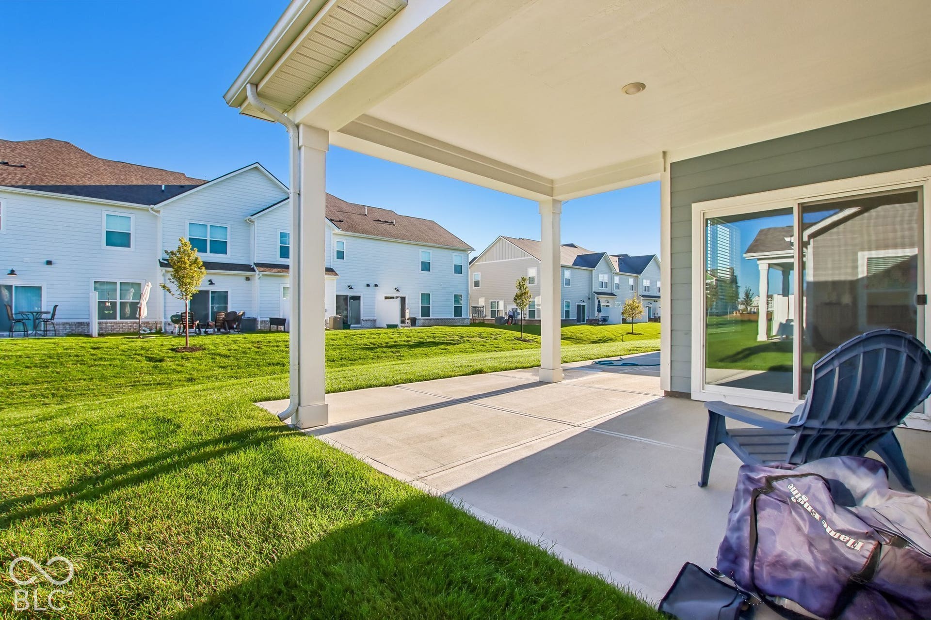 Covered patio with a concrete surface, white support columns, and an exterior sliding glass door