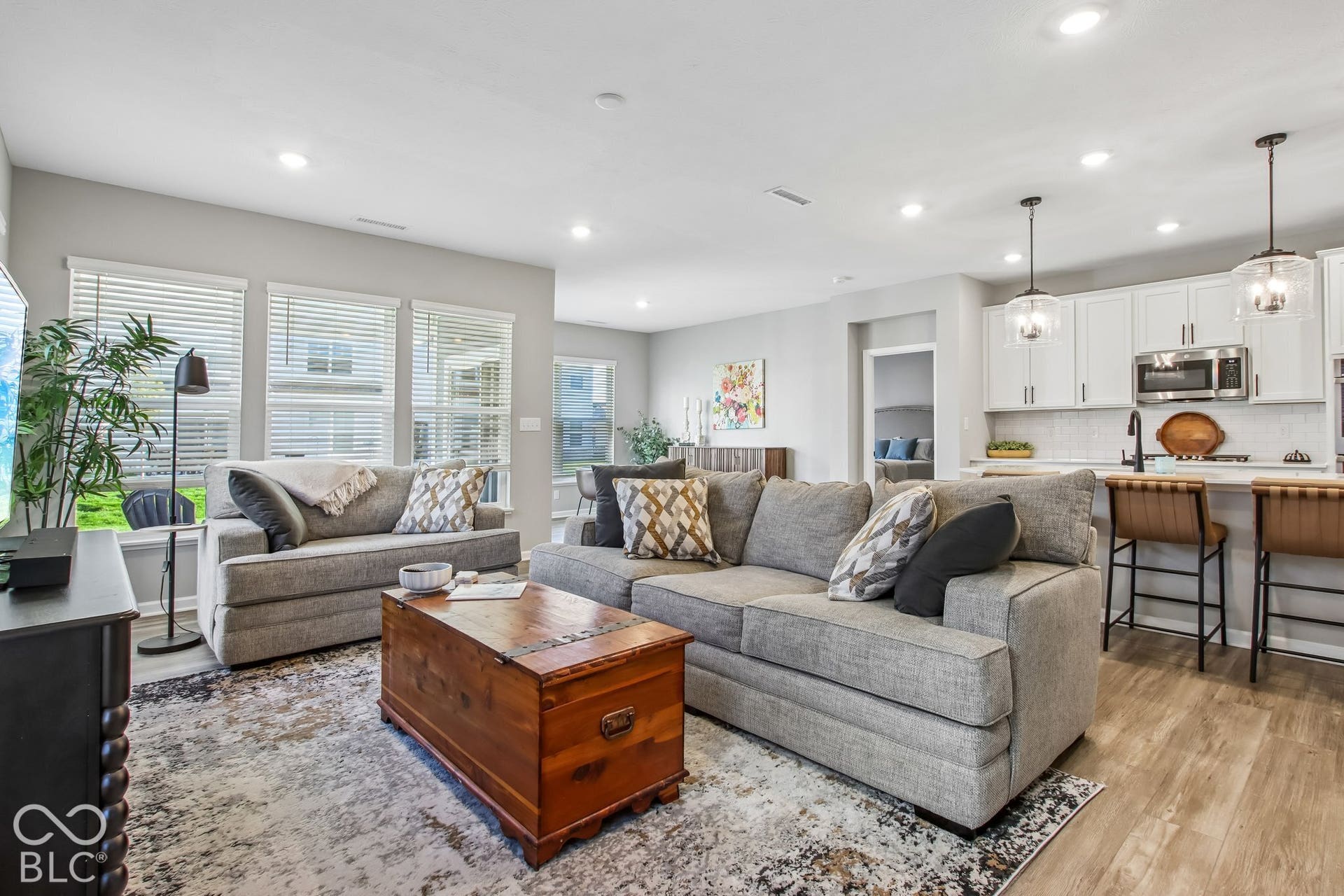 Open-concept living area featuring wood-finish flooring, recessed lighting, and large windows