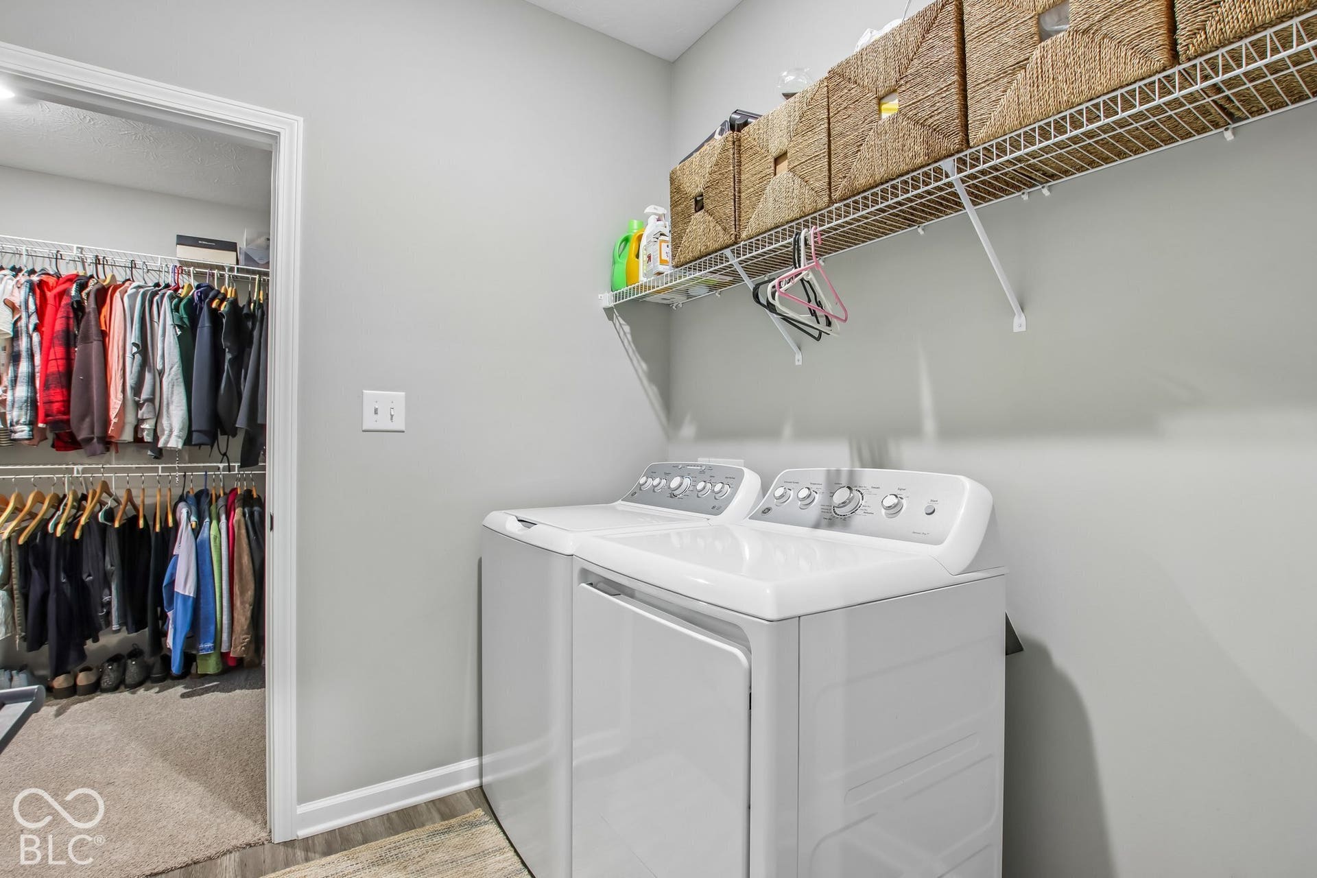Laundry area with wood-finish flooring, light gray walls, and white appliances