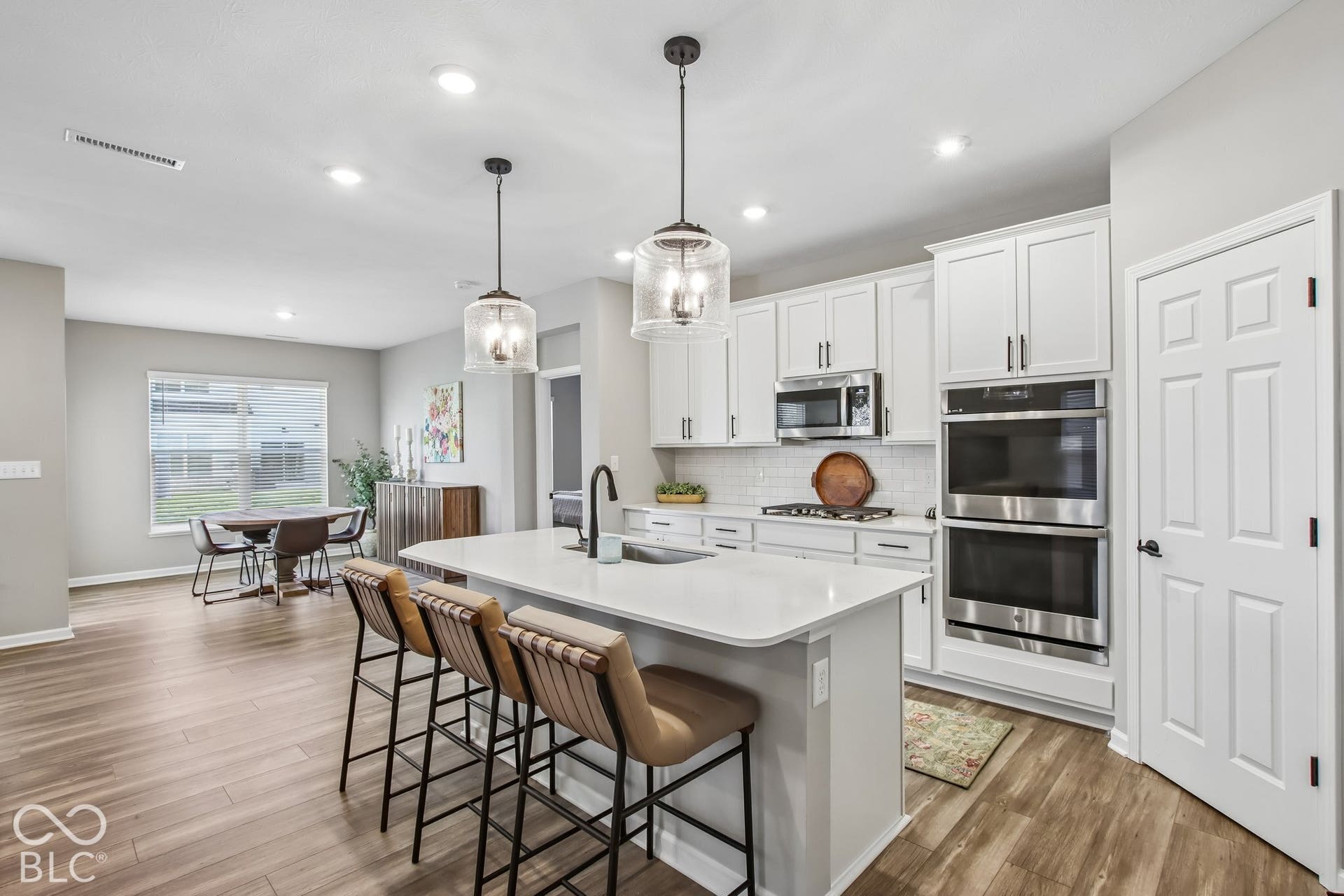 Contemporary kitchen featuring white cabinetry, a large center island with seating, stainless steel double ovens, a gas range, and wood-finish flooring