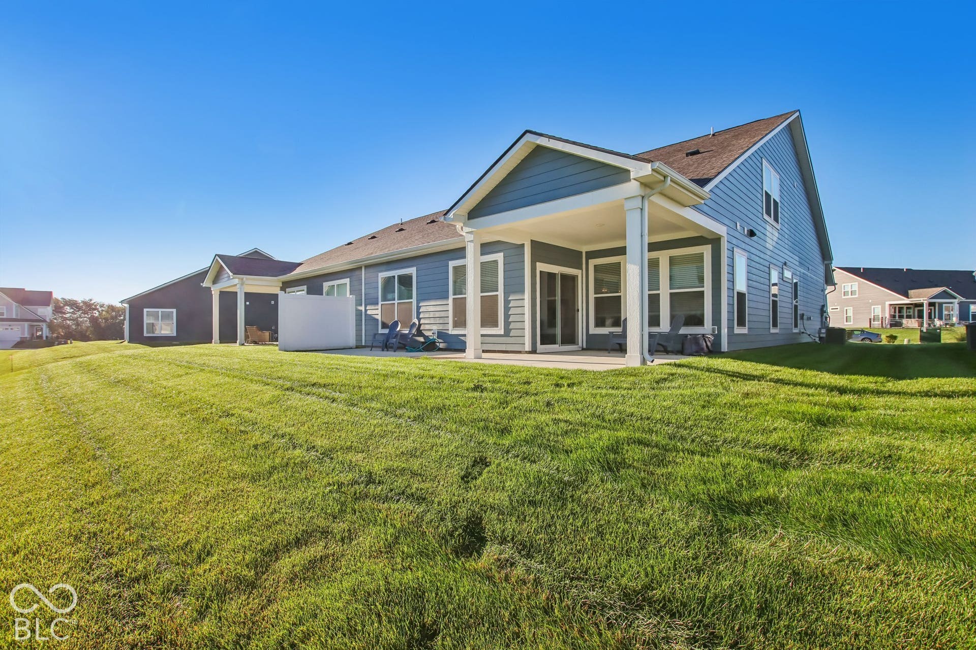 Expansive green lawn bordering a covered patio and a concrete patio