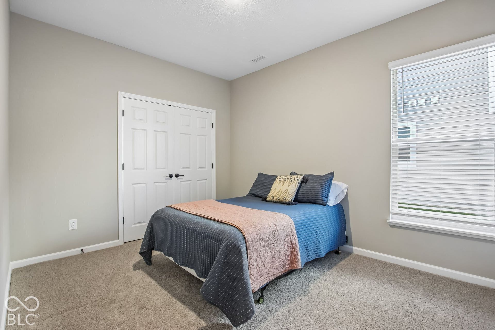 Neutral wall color, carpeted flooring, window with blinds, and paneled closet doors