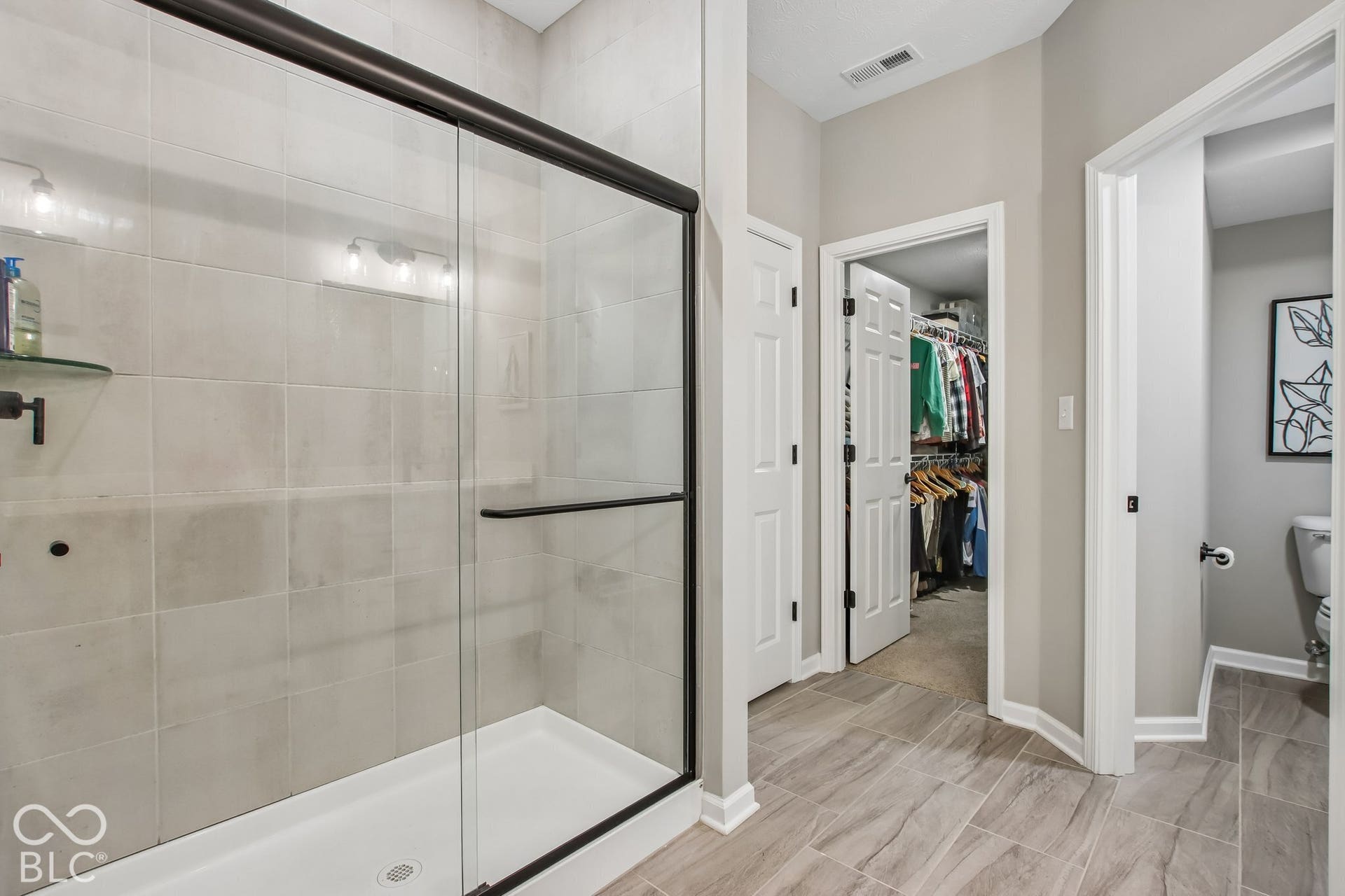 Glass-enclosed shower with a black frame and light-toned tile surround