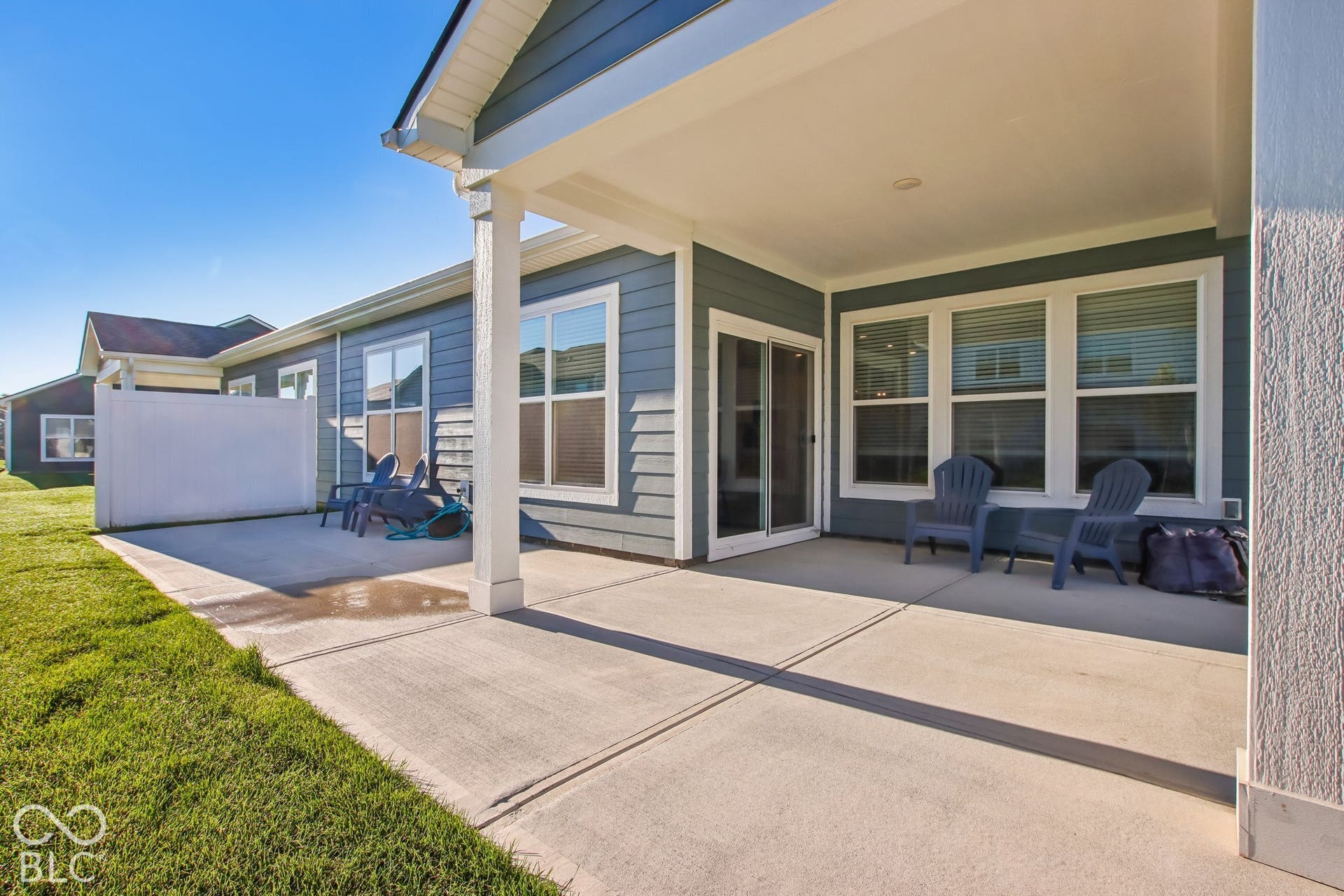 Expansive covered patio with composite decking and ceiling fans, opening to a manicured lawn