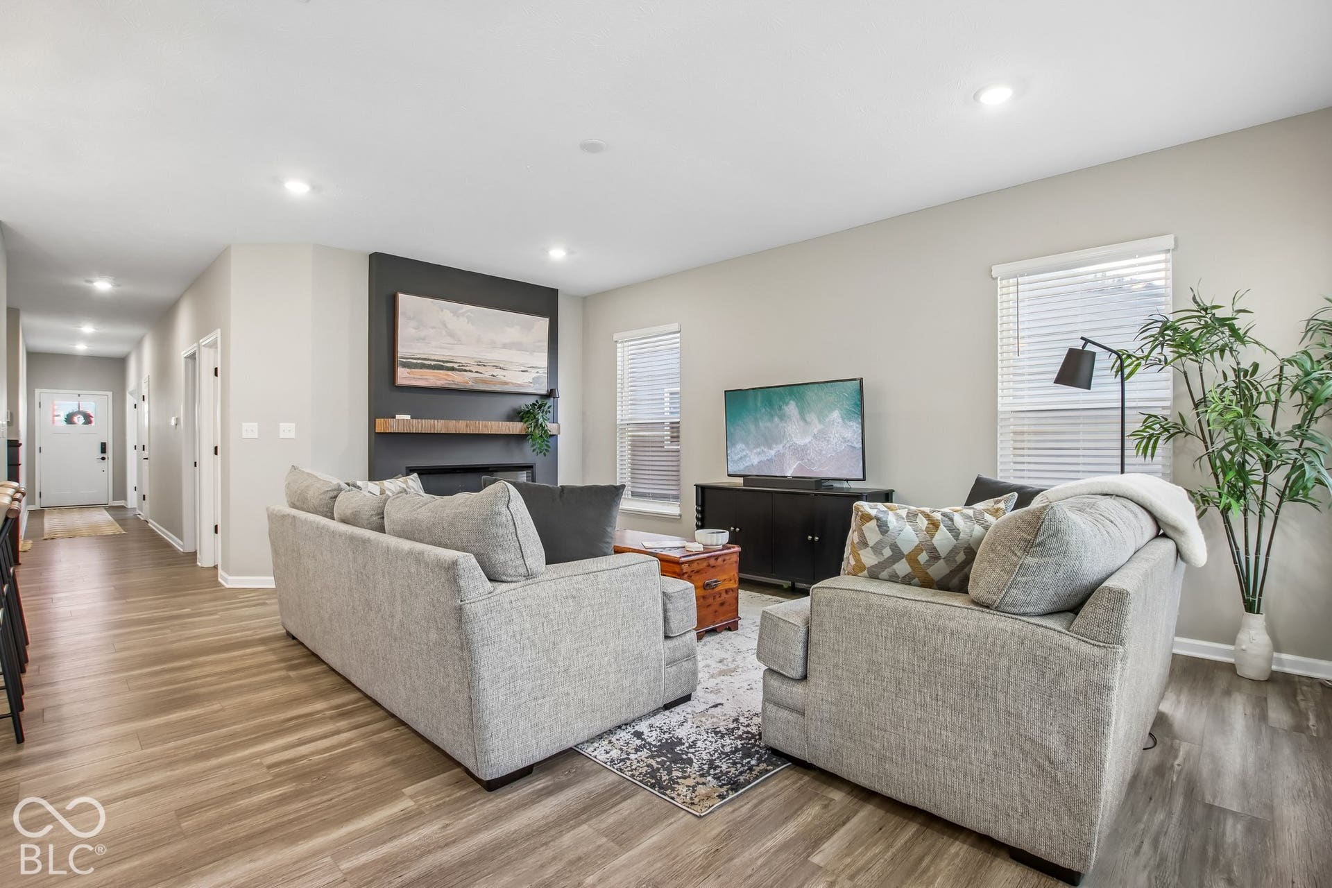 Wood-finish flooring throughout, recessed ceiling lighting, a fireplace with a wood mantle, and window blinds