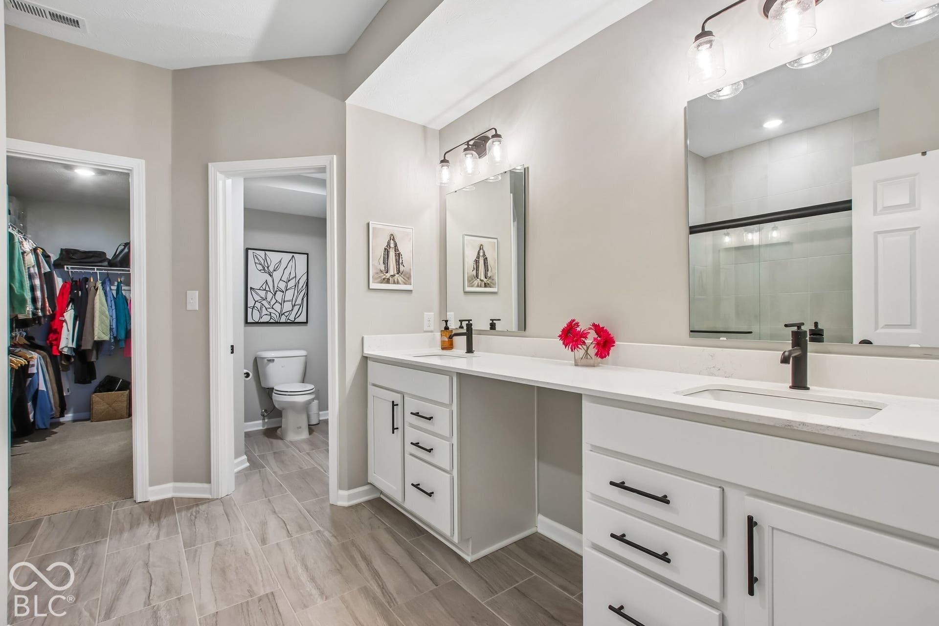 Bathroom featuring dual vanity with white cabinetry, matte black hardware, integrated sinks, and light-toned countertops