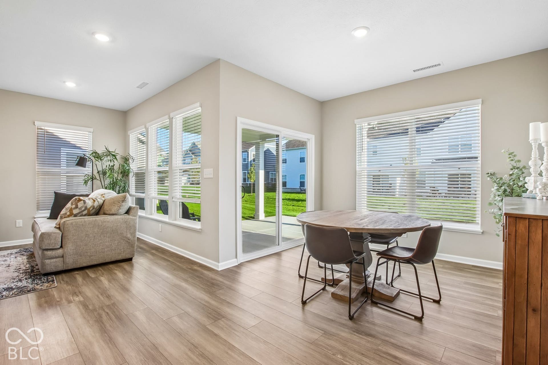 Wood-finish flooring throughout, recessed lighting, multiple large windows, and a sliding glass door to an outdoor living space