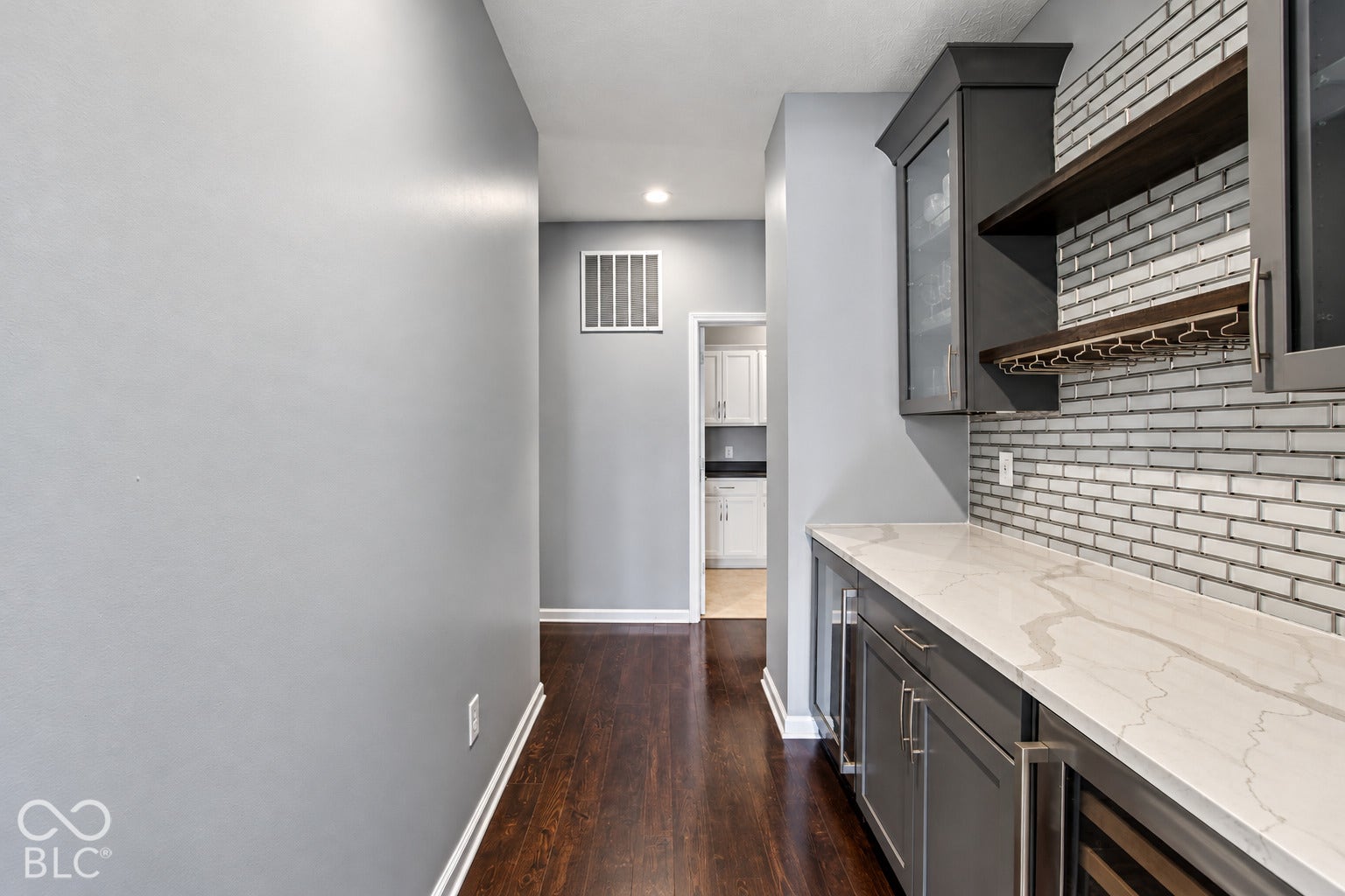 Wet bar featuring quartz countertops, dark cabinetry, and a subway tile backsplash