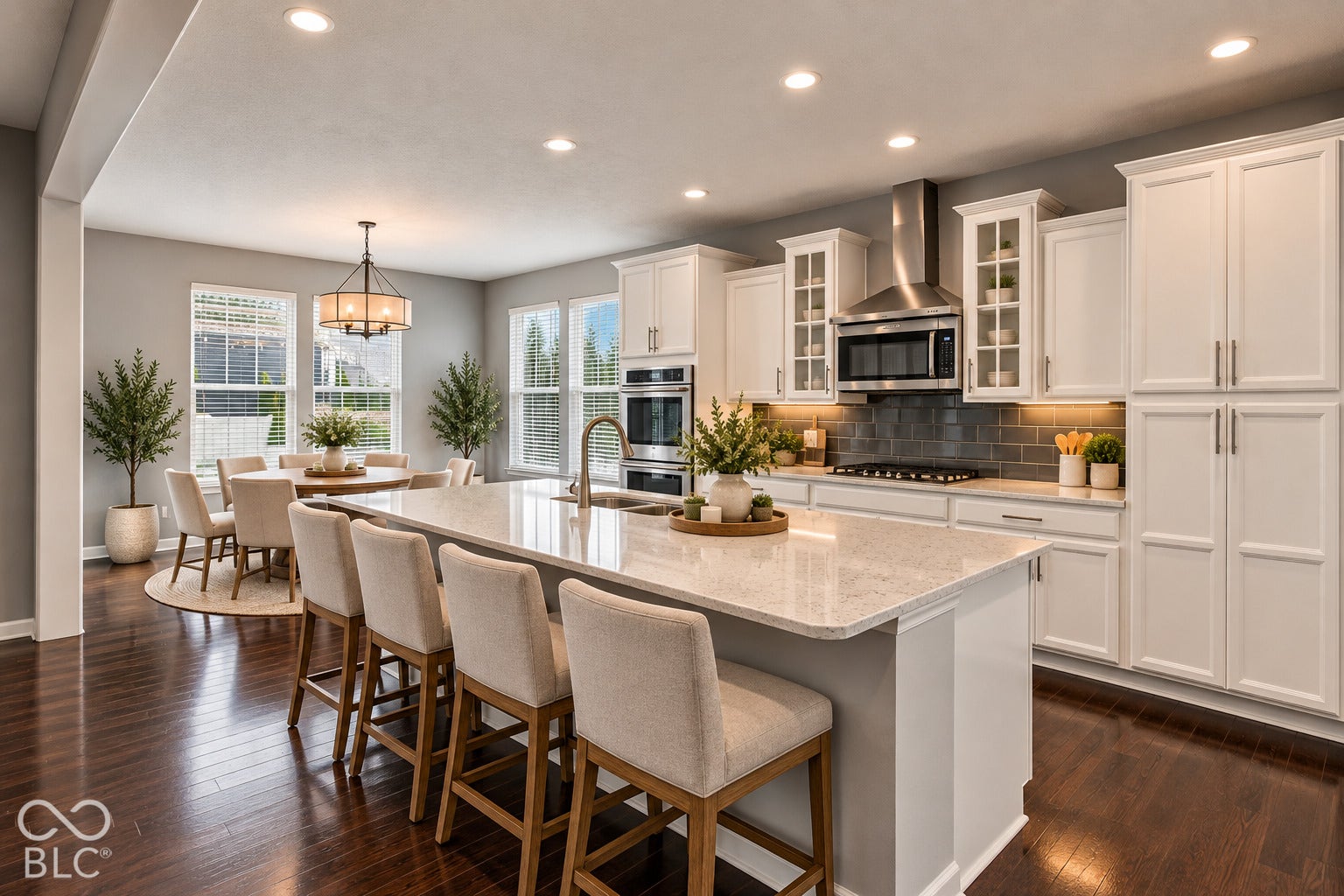 Gourmet kitchen with white cabinetry, stainless steel appliances, a large central island with seating, and wood-finish flooring