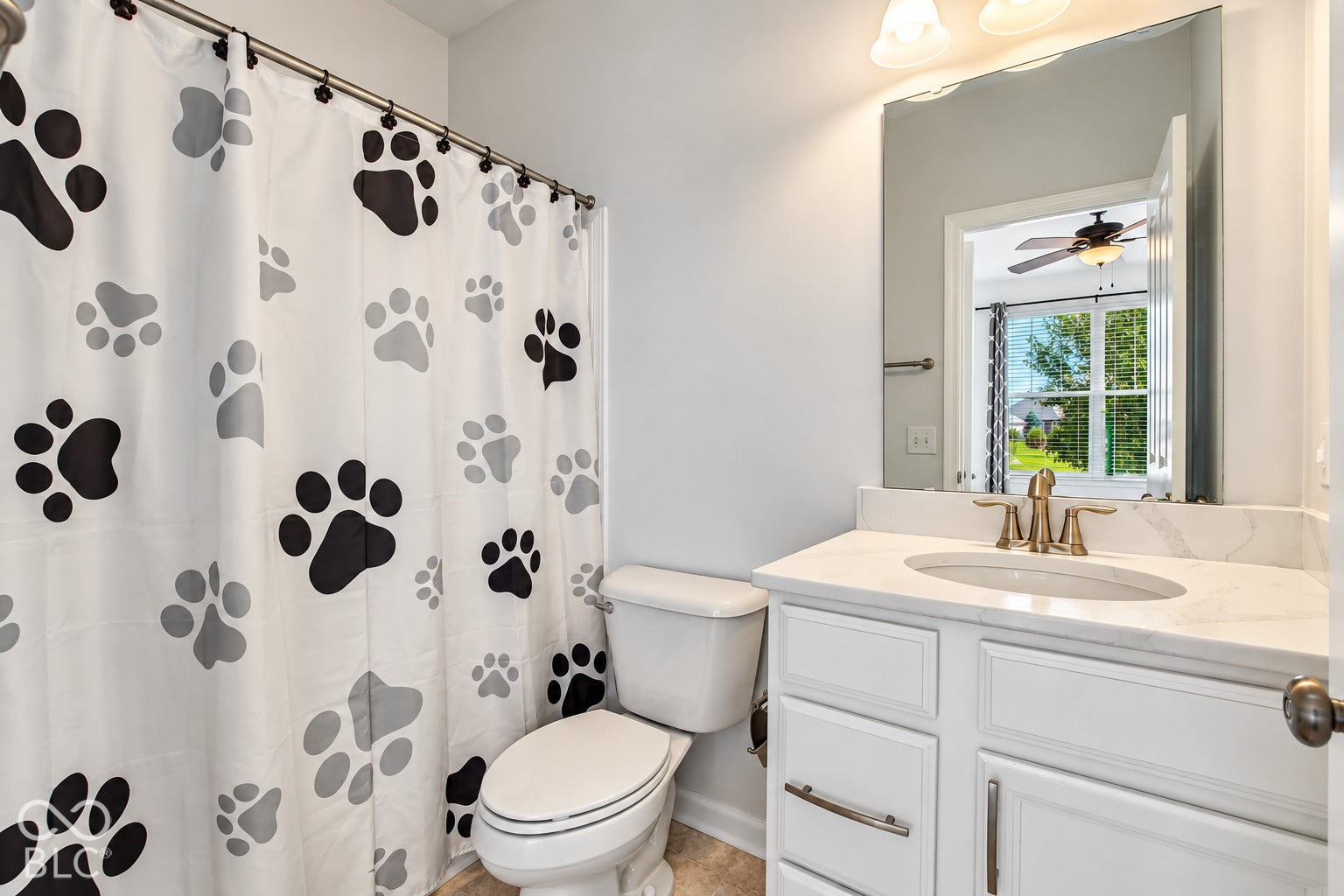 White vanity with a neutral countertop, undermount sink, and brass-tone fixtures