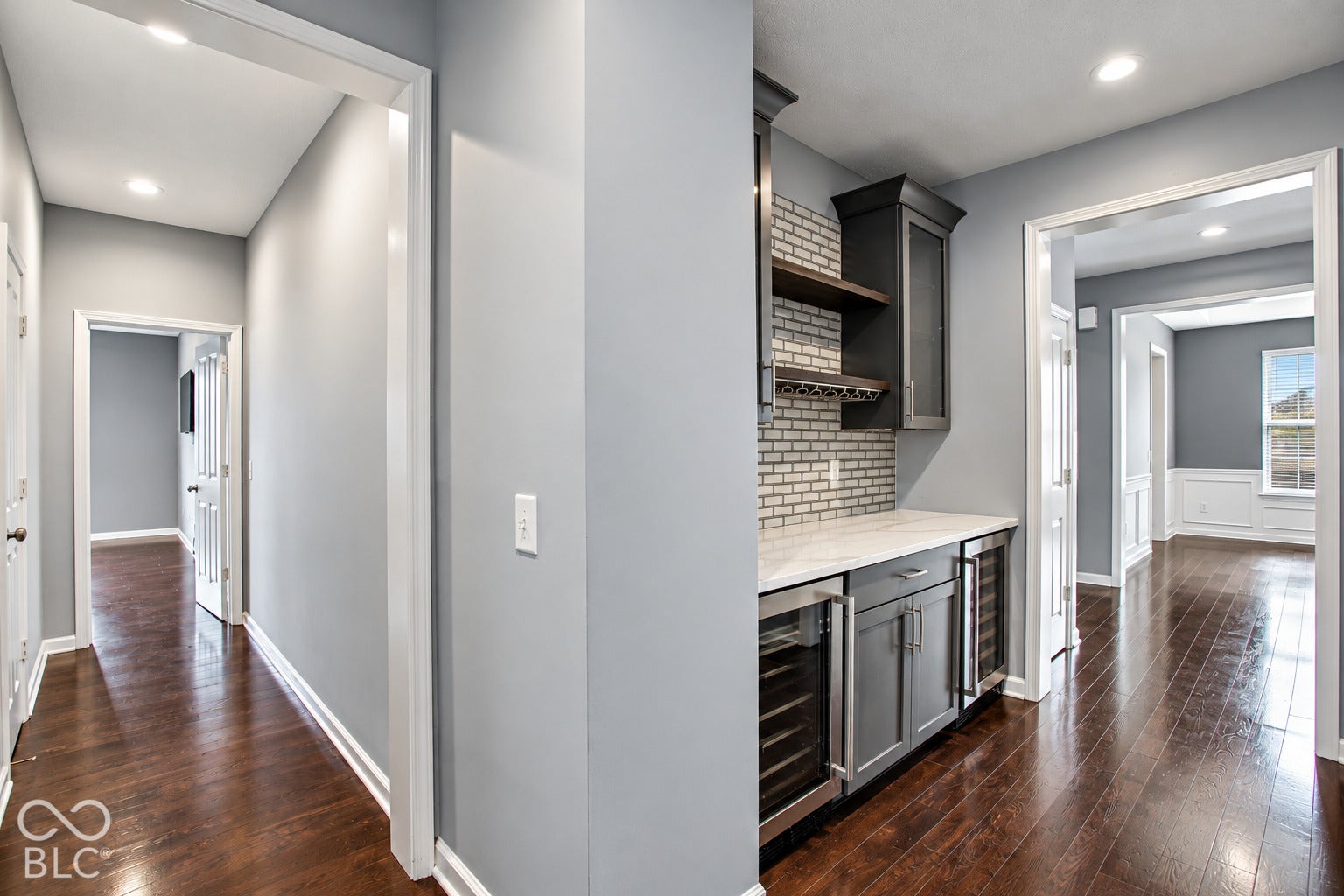 Built-in wet bar with white subway tile backsplash, white countertop, dark cabinetry, and integrated beverage coolers