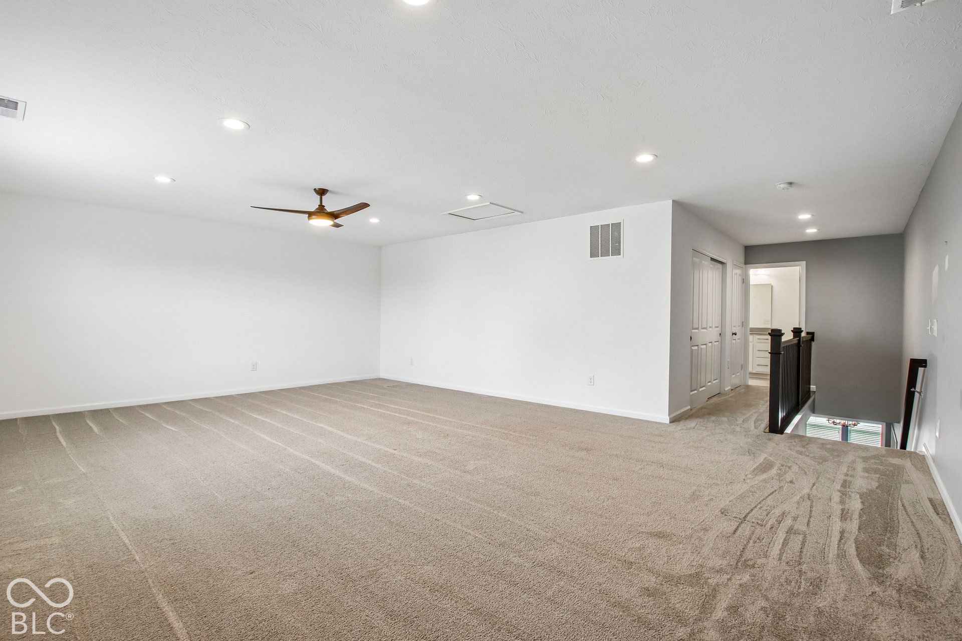 Expansive carpeted area featuring recessed lighting, a ceiling fan, and a built-in closet with bi-fold doors