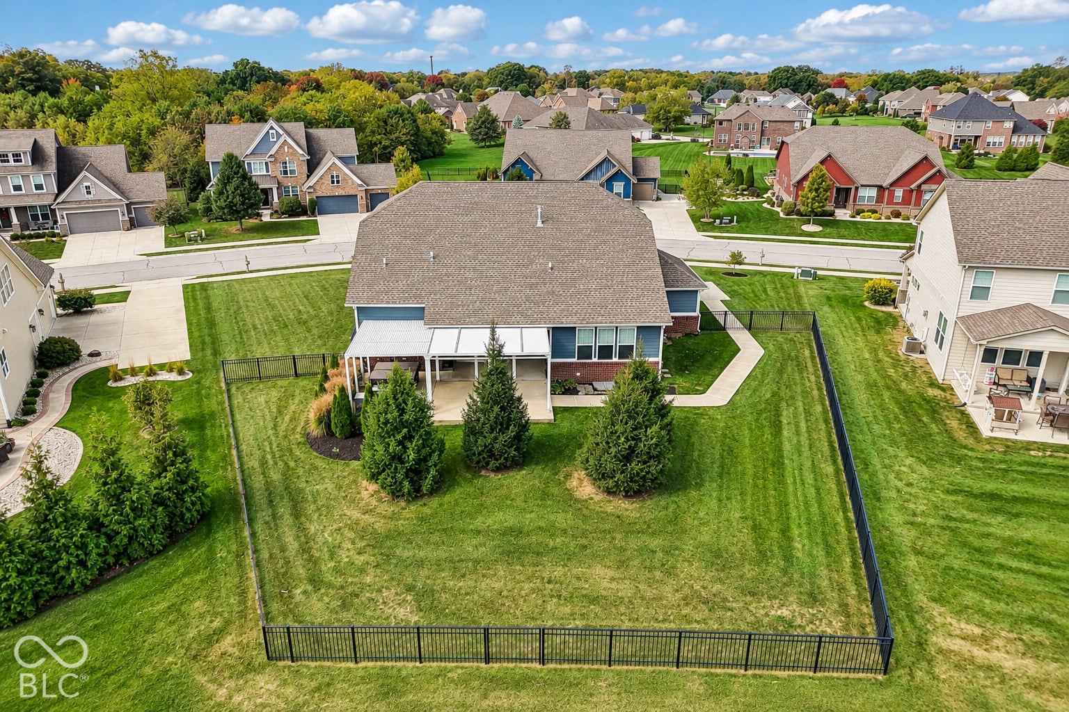 Expansive fenced backyard with a covered patio, mature landscaping, and an additional open-air patio area