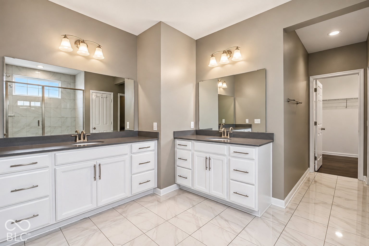 Dual white vanity cabinets with brushed nickel hardware, expansive countertop space, and large mirrors