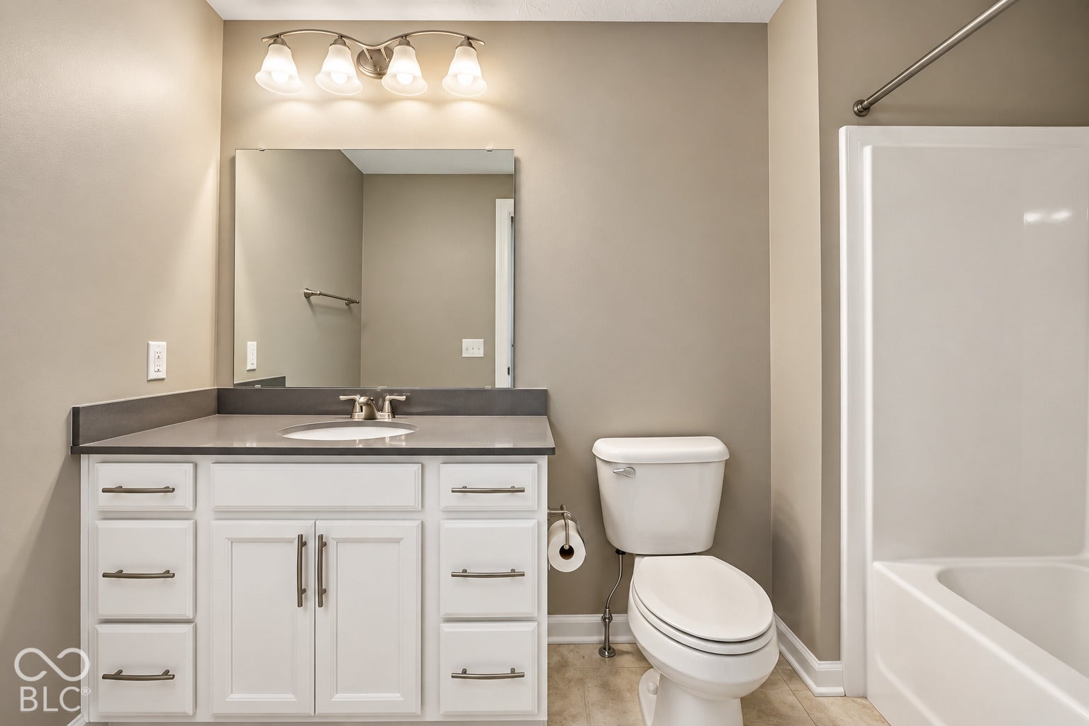 White vanity with a gray countertop, an undermount sink, and a framed mirror