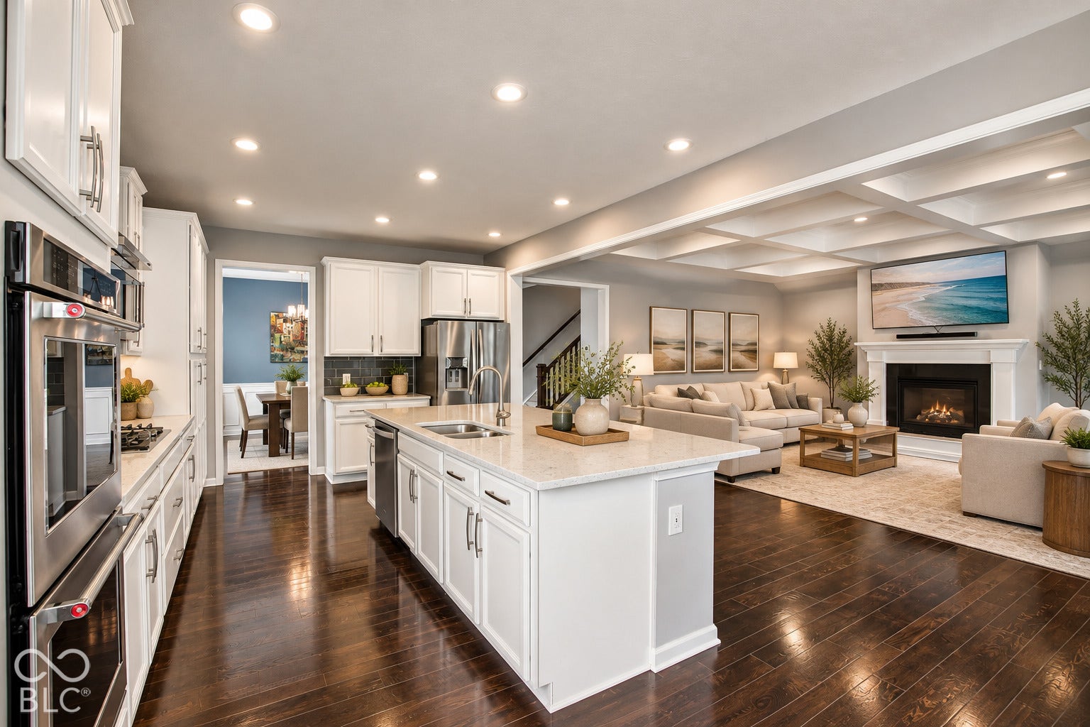 Spacious open-concept layout featuring wood-finish flooring, a kitchen island with a built-in sink, and stainless steel appliances