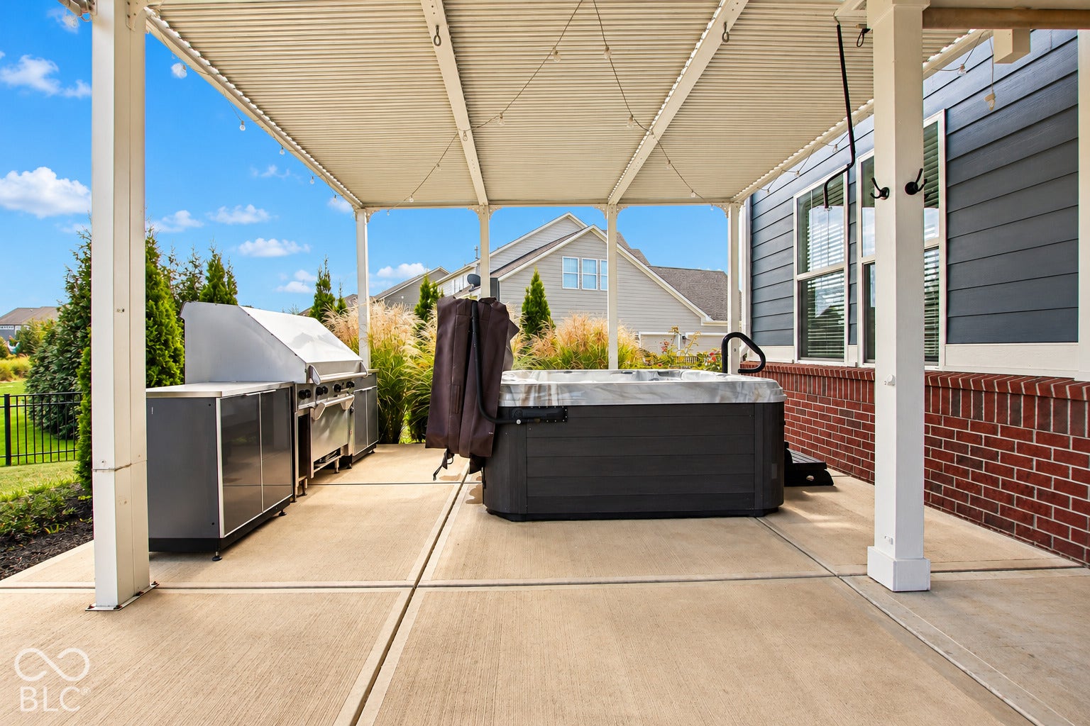Covered patio featuring an outdoor kitchen, hot tub, and concrete flooring