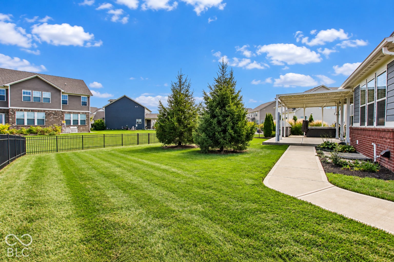 Expansive lawn with mature evergreens and a concrete walkway