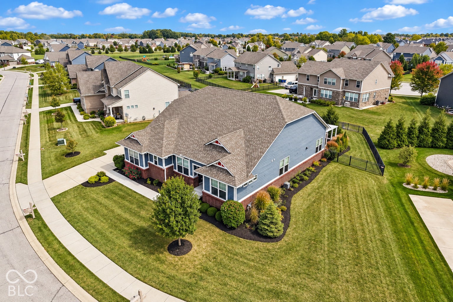 Two-story residence featuring blue siding with brick accents, a gabled roof, and landscaped grounds