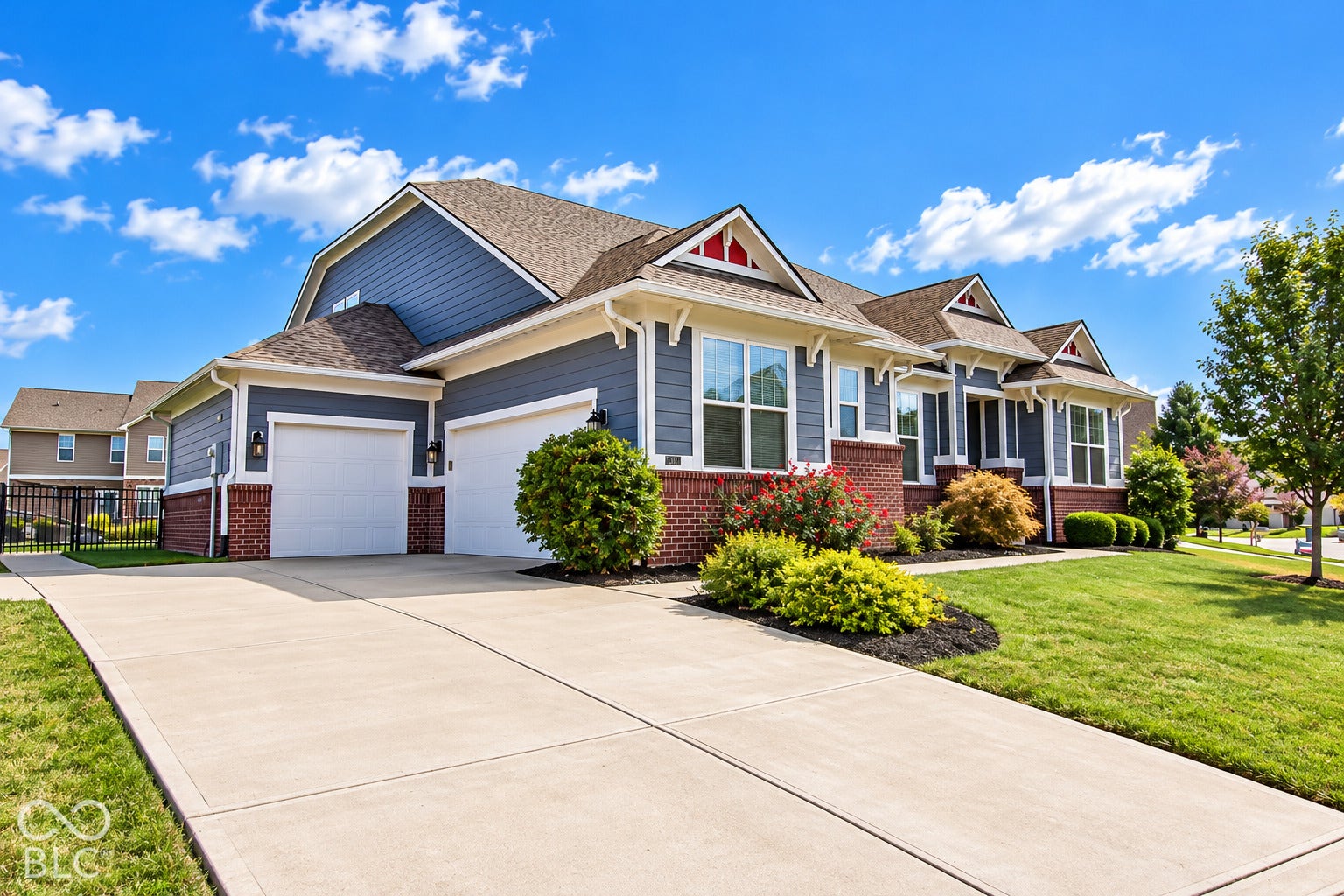 Two-car garage with white doors, brick and siding exterior, concrete driveway, and established landscaping