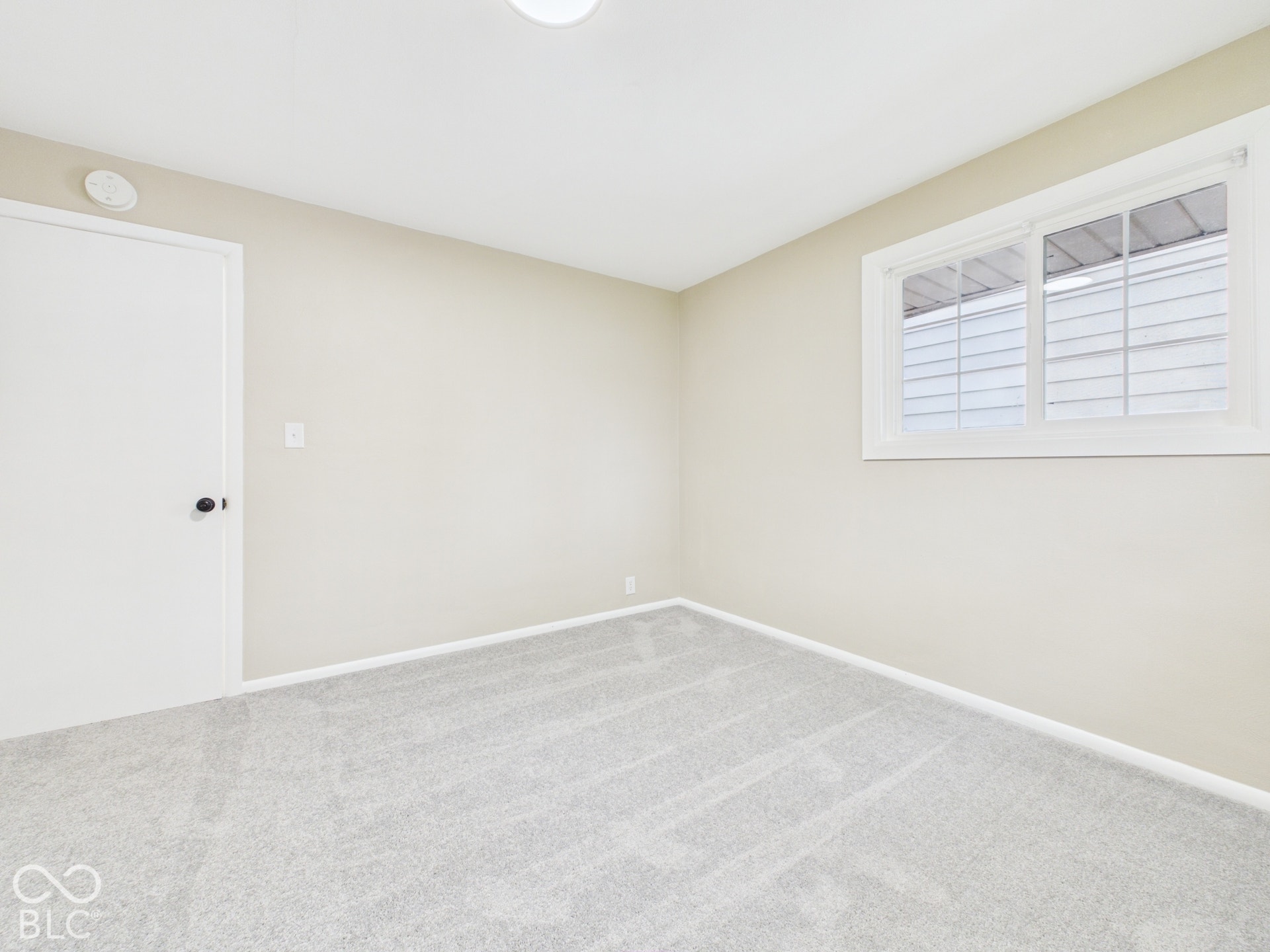 Light-colored carpeting, neutral wall paint, and a white framed window