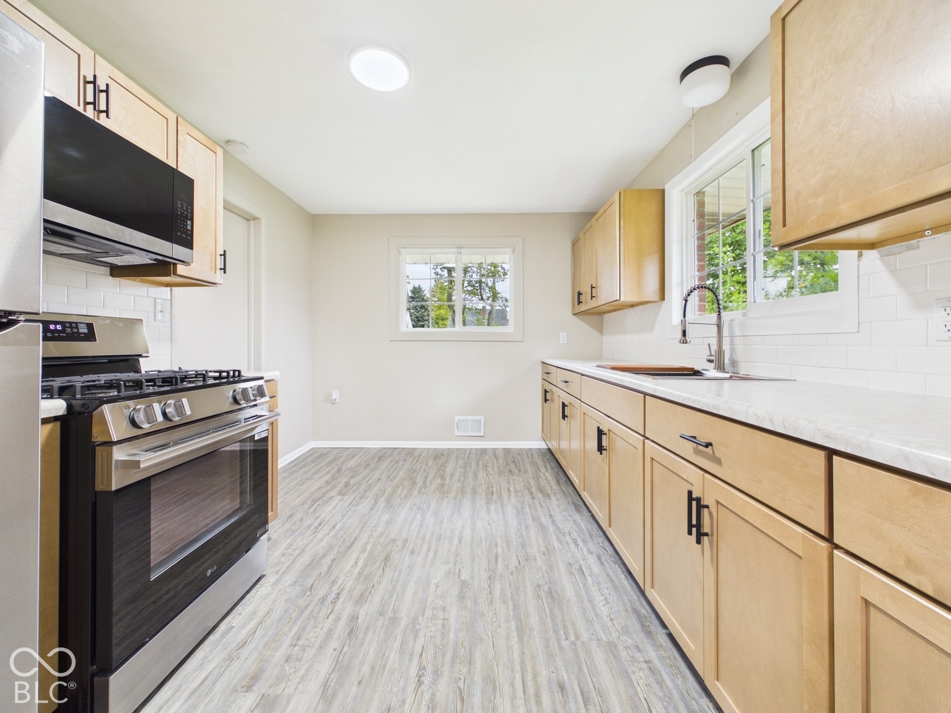 Kitchen with light wood-finish cabinetry, stainless steel appliances, and wood-finish flooring