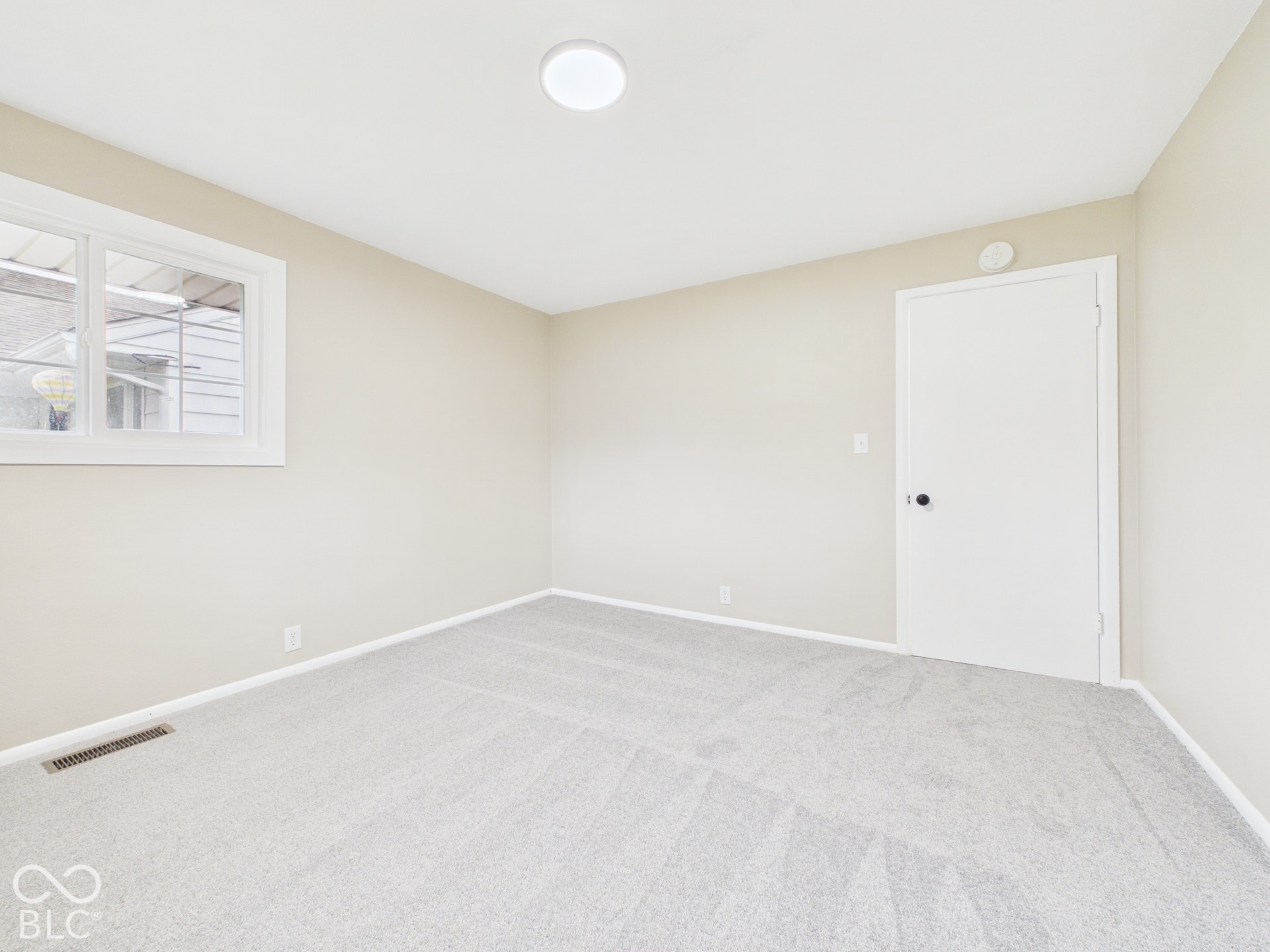 Neutral wall color, light-toned carpeting, white trim, and a window with white framing