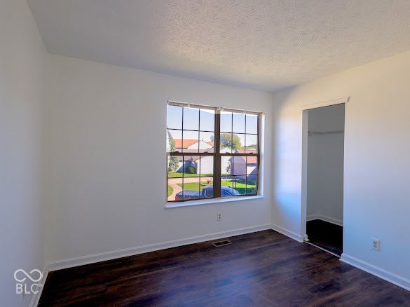 Wood-finish flooring, white walls, and a window with grid panes