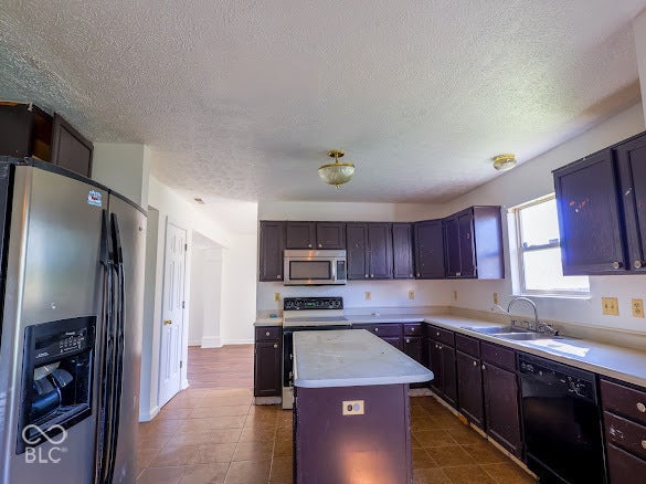 Kitchen with dark wood-finish cabinetry, stainless steel refrigerator, stainless steel microwave, and white countertops