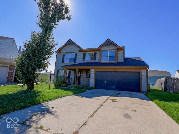 Two-story residence with light gray siding, dark gray garage door, covered front porch, and a concrete driveway