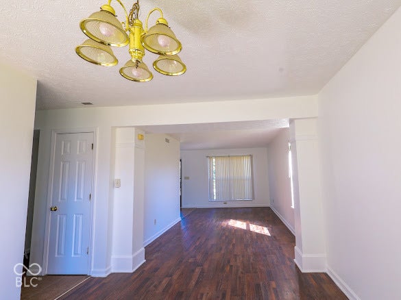 Expansive interior featuring wood-finish flooring, a decorative five-light chandelier, a paneled door, and a wide cased opening