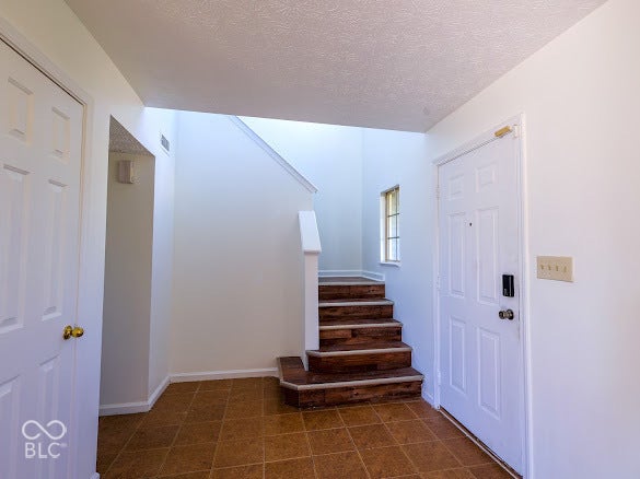 Entryway featuring tile flooring, a staircase with wood-finish treads, and a paneled entry door
