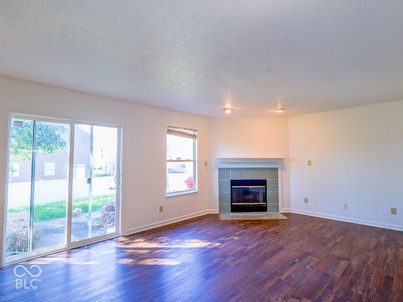 Wood-finish flooring, sliding glass door, single pane window, tile-surround fireplace, and recessed lighting