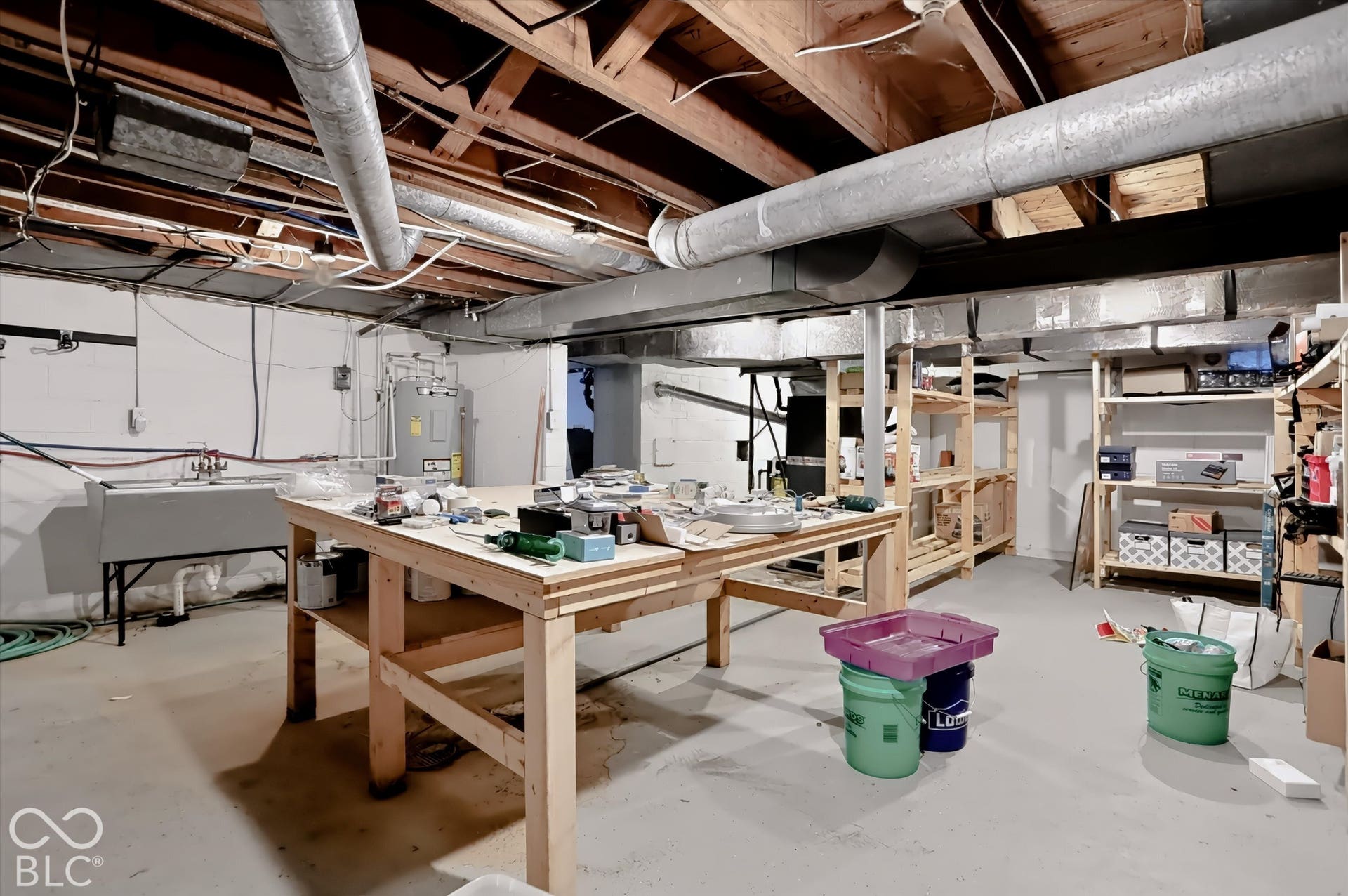 Utility sink, exposed ceiling joists, concrete flooring, overhead ductwork, built-in shelving