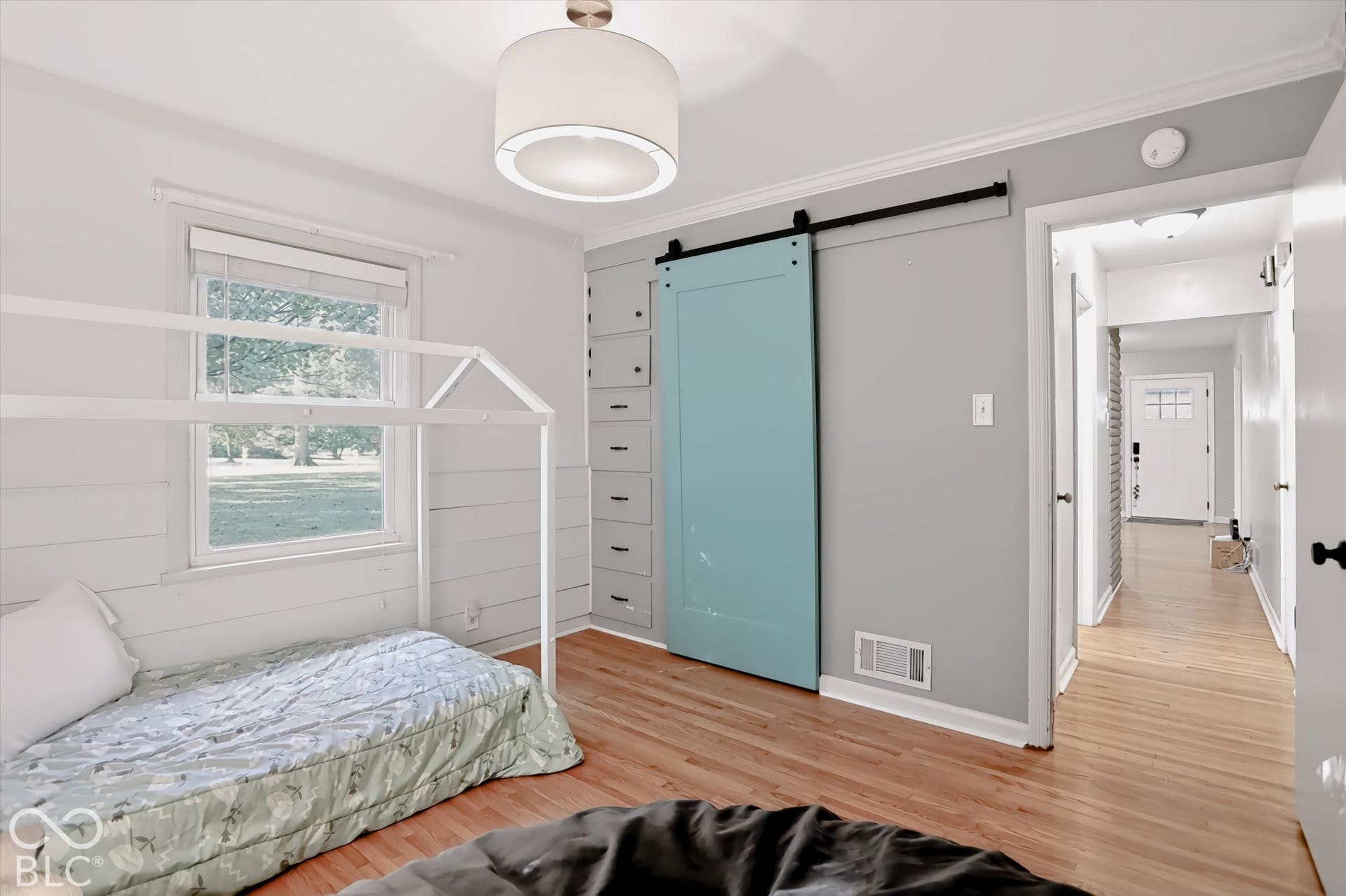 Hardwood-finish flooring, built-in storage with multiple drawers, modern barn door, contemporary flush mount lighting, and a large window