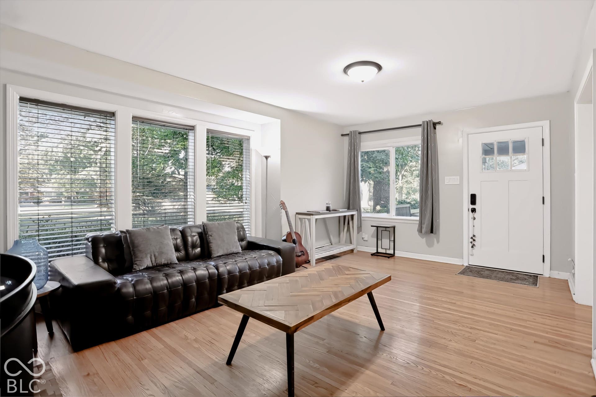 Hardwood flooring throughout, a front entry door with privacy glass, recessed ceiling lighting, a bay window with multiple panes, and light-toned wall finishes