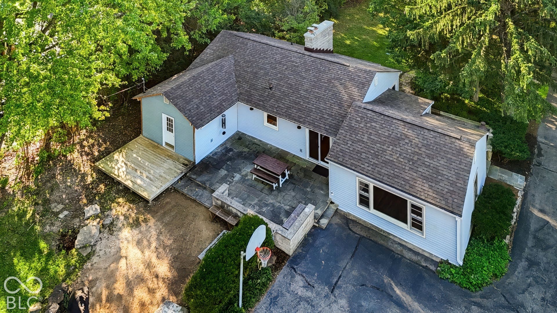 Spacious outdoor patio with stone pavers, expansive driveway, and a newly constructed wood deck