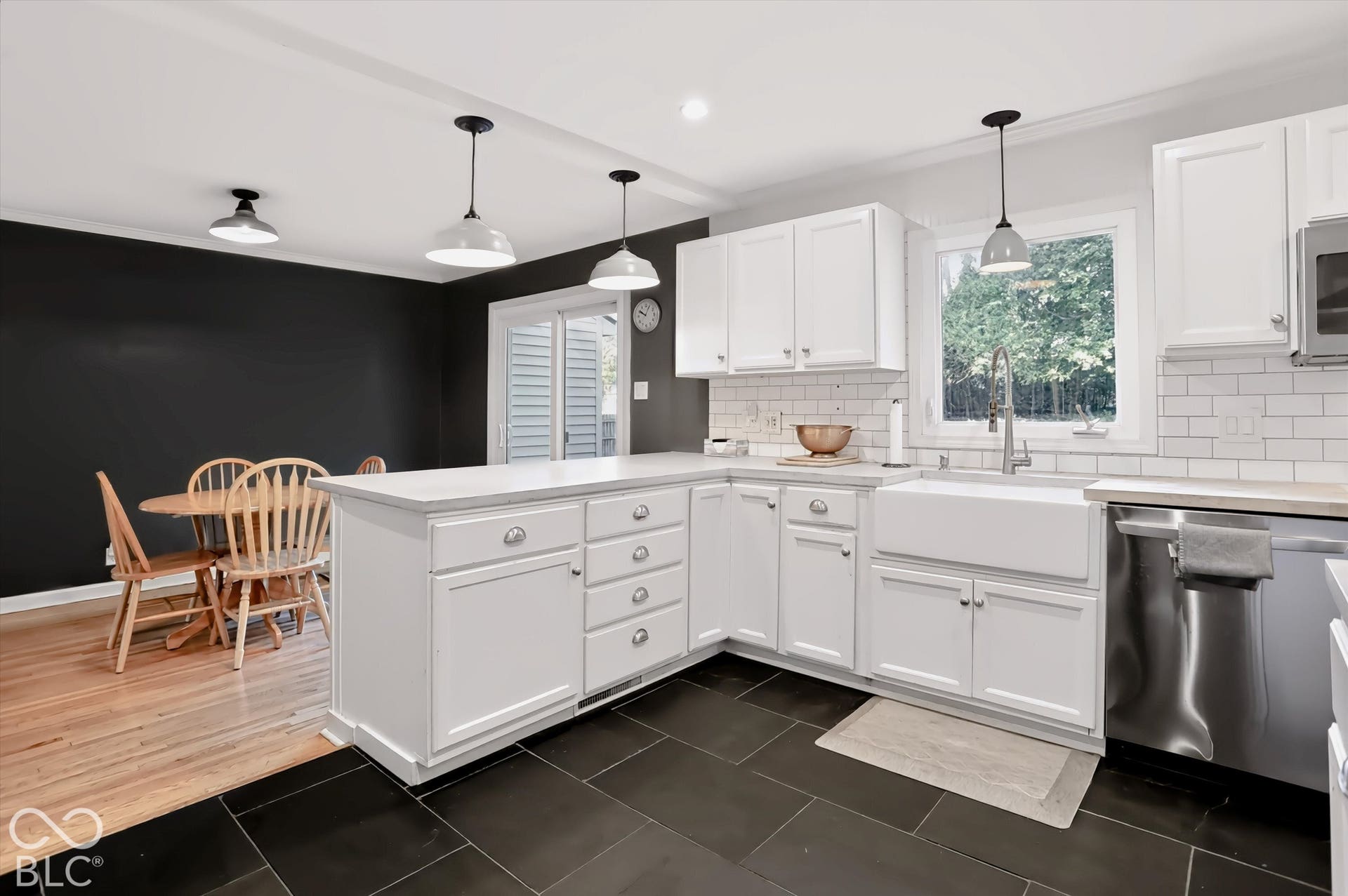 White shaker-style cabinetry with ample storage, a large farmhouse sink, stainless steel appliances, and subway tile backsplash