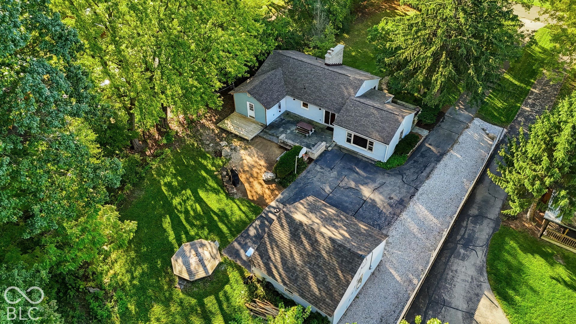 Expansive lot featuring mature trees, a multi-level deck, paved driveway, and a detached auxiliary structure