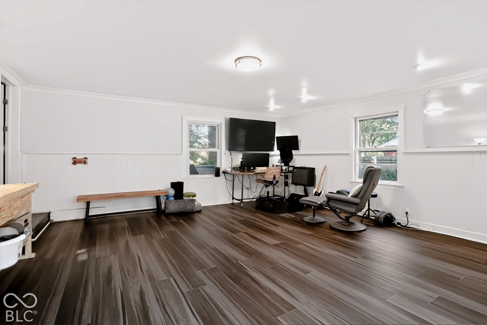 Spacious room featuring wood-finish flooring, white paneled wainscoting, and recessed lighting