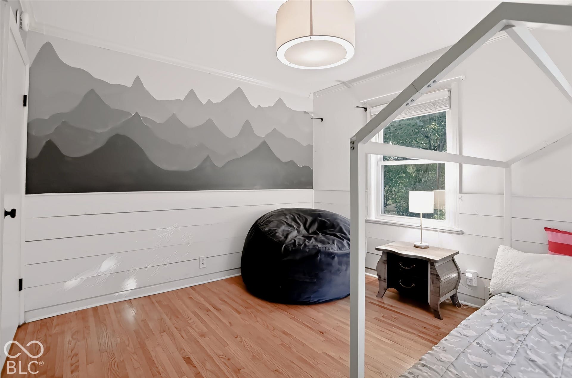Hardwood flooring, painted accent wall, drum pendant light fixture, window with natural light, and shiplap wall treatment