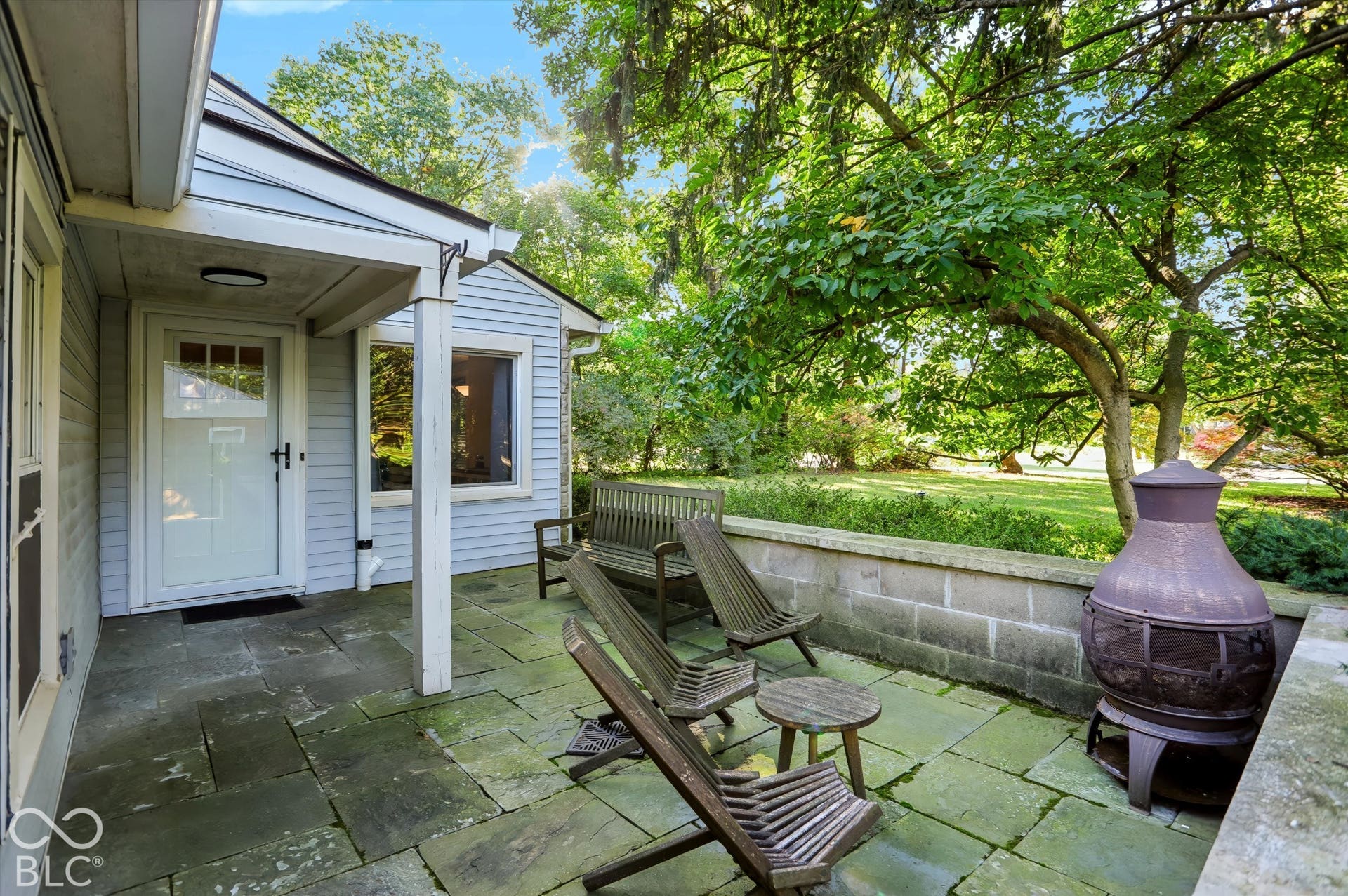 Stone patio featuring a low block wall and expansive green space