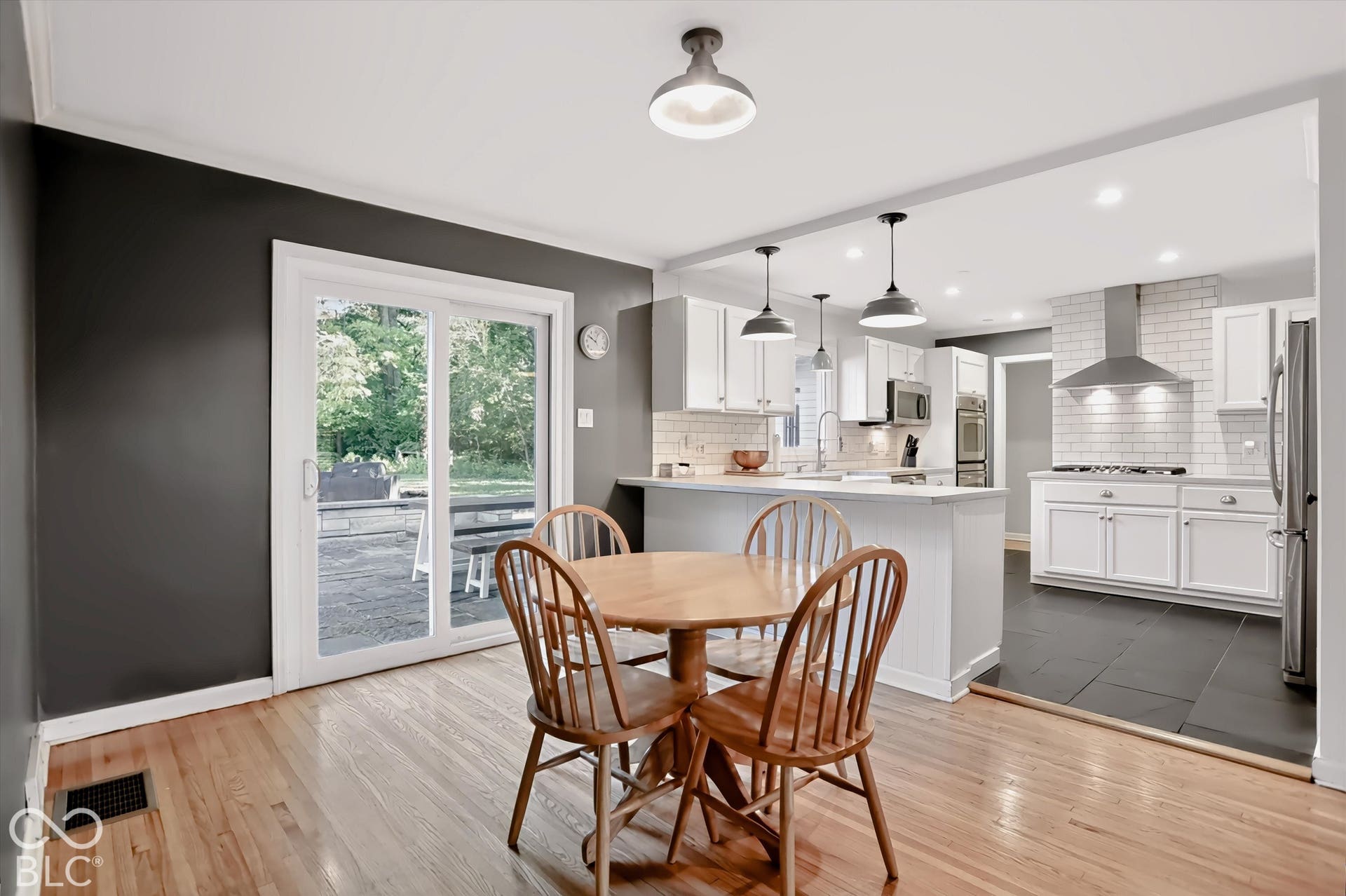 Hardwood flooring, sliding glass door, recessed lighting, white cabinetry, and a subway tile backsplash