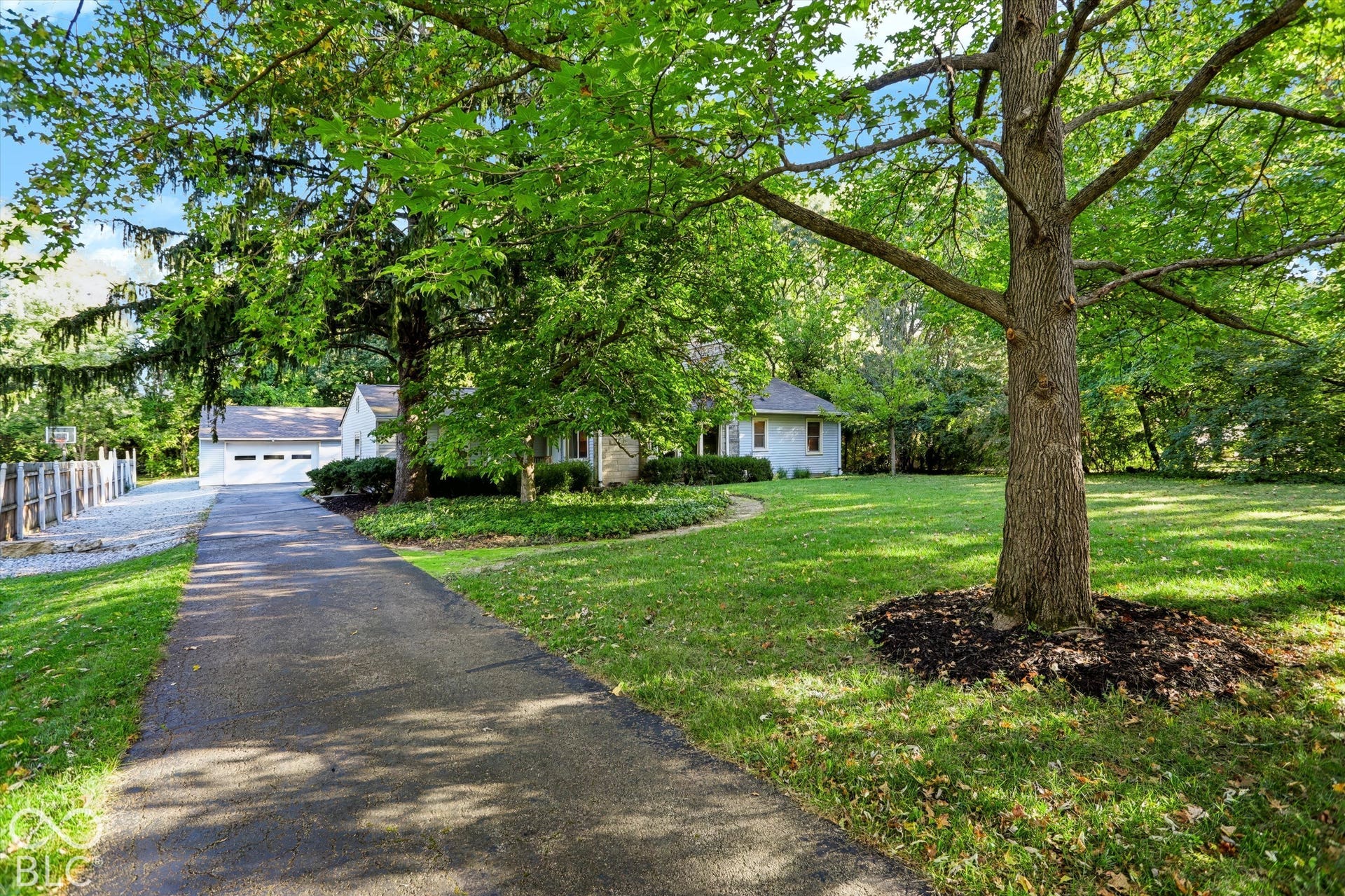 Spacious asphalt driveway leading to a detached garage