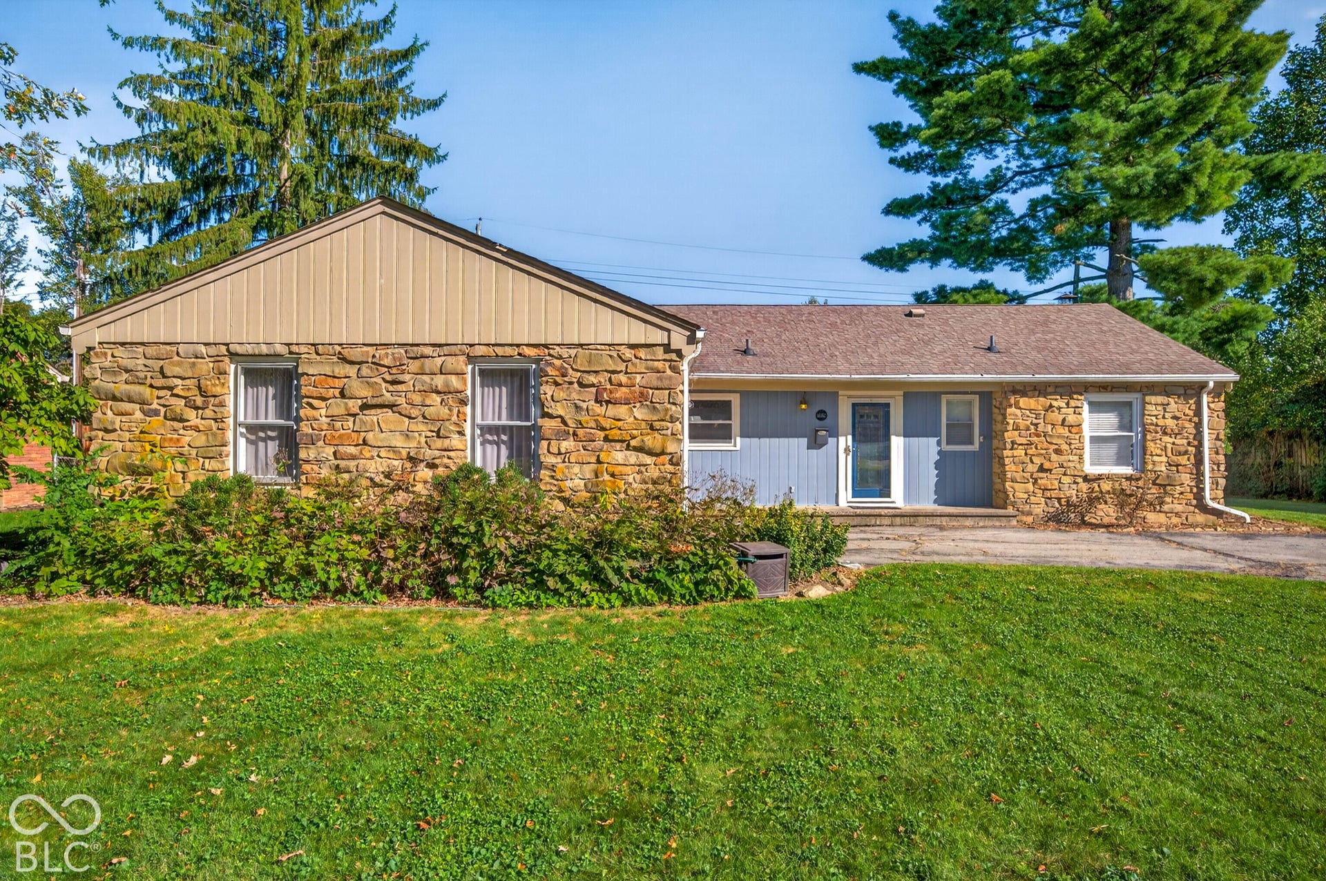 Stone and siding exterior with a shingle roof and mature landscaping